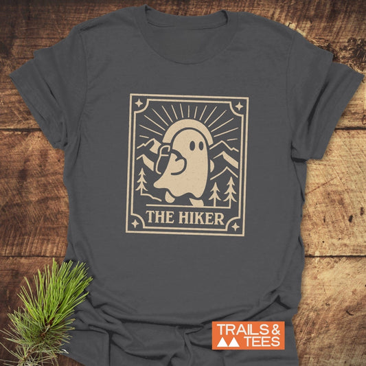 The Hiker Retro Tarot T-Shirt featuring a ghost hiker graphic with pine trees and sunbeams, emphasizing outdoor adventure spirit and crafted for comfort.