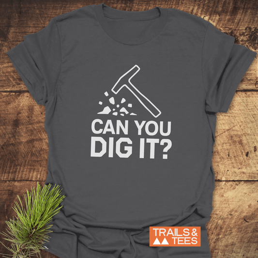 Can You Dig It? Rock Lovers T-Shirt featuring a hammer graphic, made from soft cotton for comfort and adventure, laid on a wooden surface.