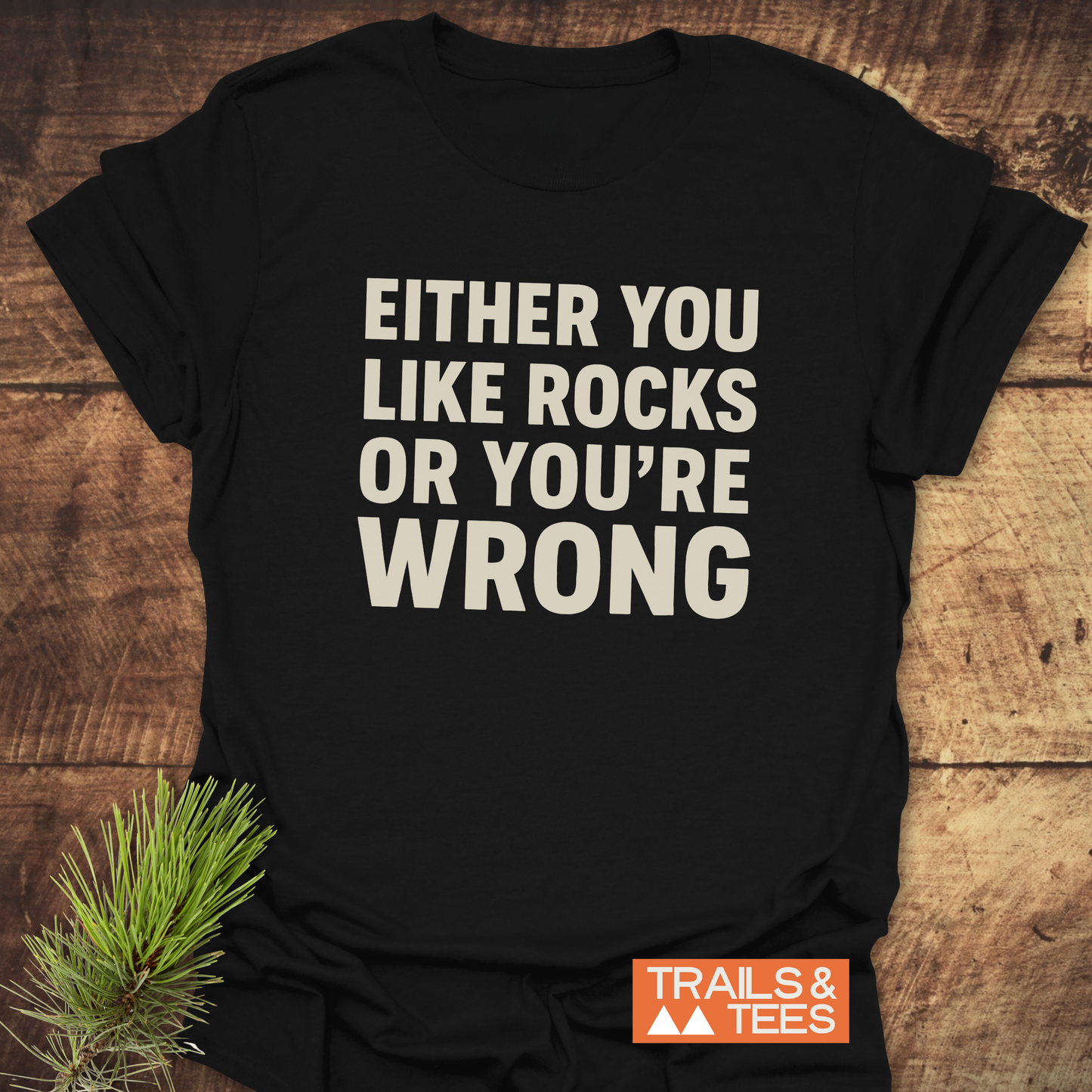 Either You Like Rocks T-Shirt on rustic wood, featuring bold off-white text and Trails & Tees logo; crafted from soft, lightweight cotton for outdoor enthusiasts.