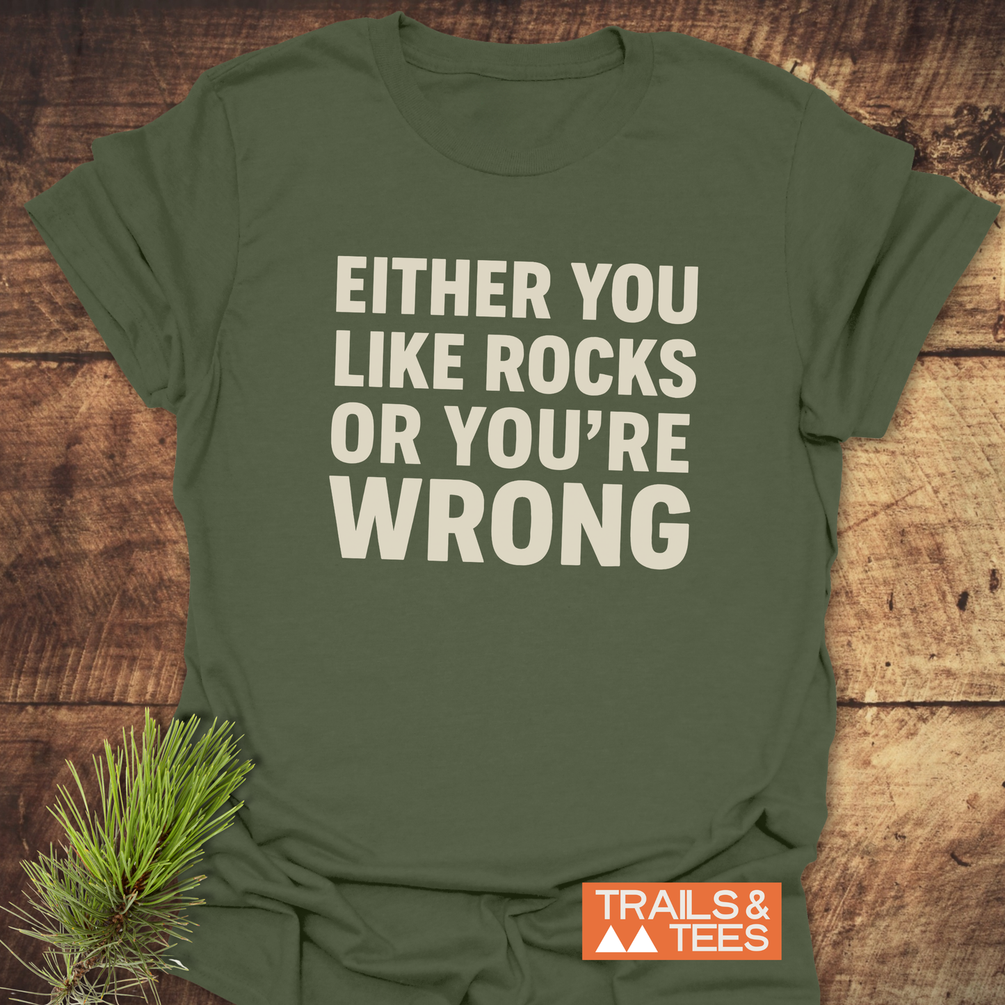 Either You Like Rocks T-Shirt on rustic wood, featuring cream slogan and Trails & Tees logo. Made from soft, durable cotton for outdoor adventures.