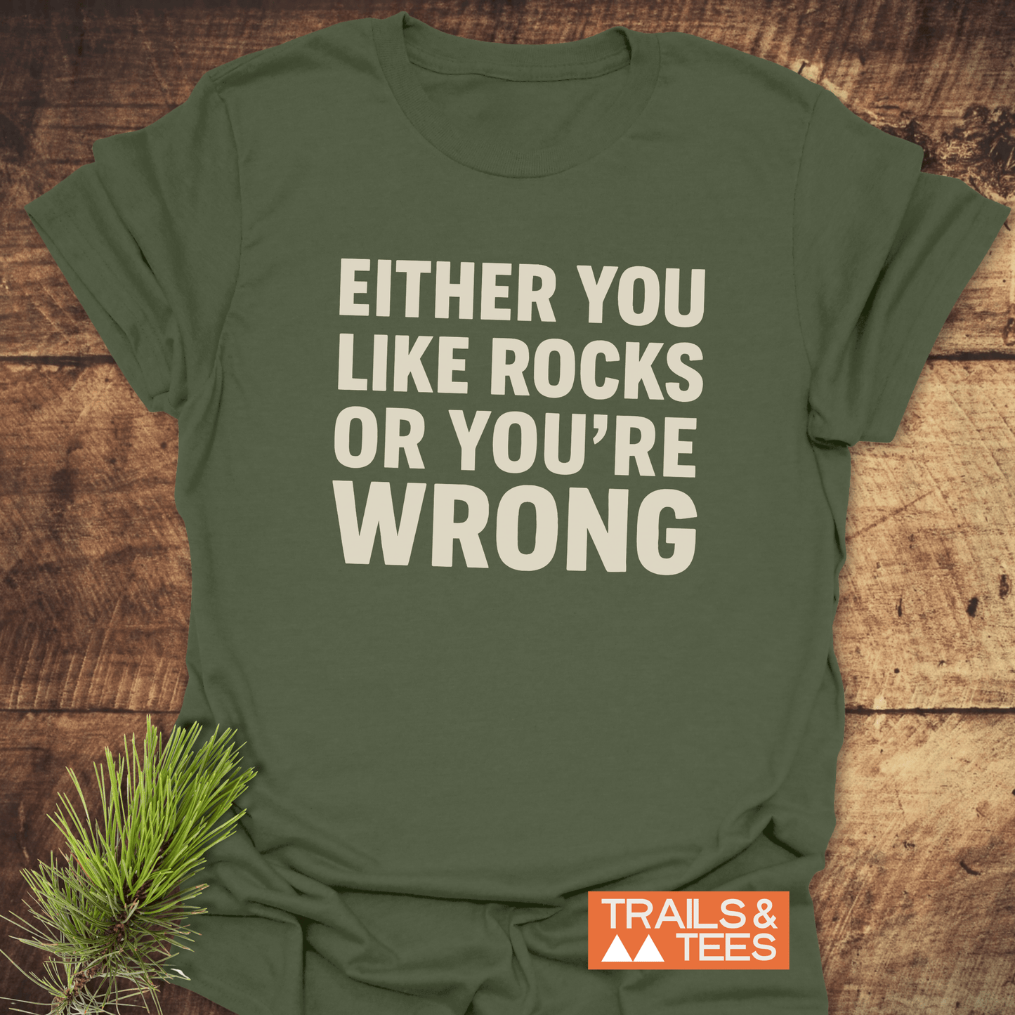 Either You Like Rocks T-Shirt on rustic wood, featuring cream slogan and Trails & Tees logo. Made from soft, durable cotton for outdoor adventures.
