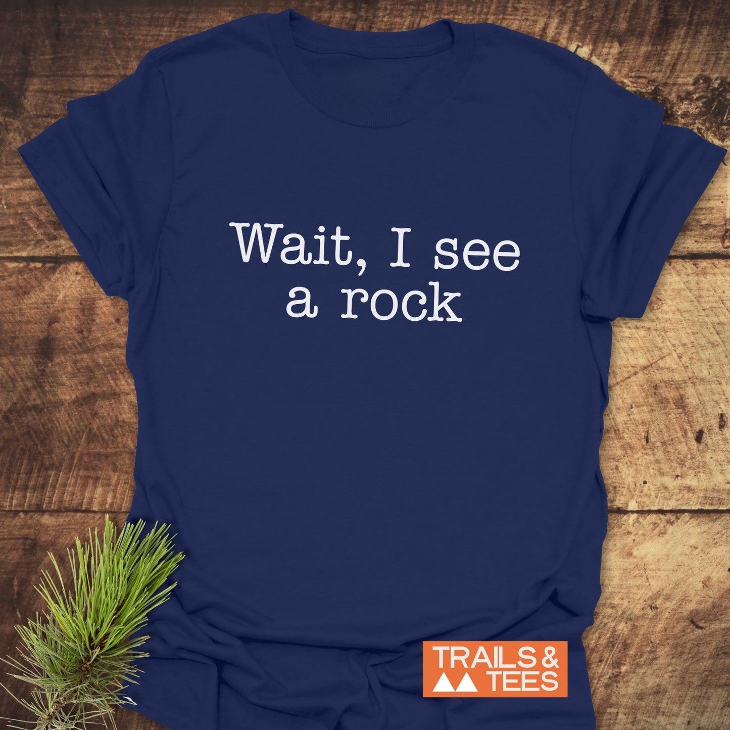 Wait, I See A Rock T-Shirt; navy, typewriter-style print, orange logo, pine branch accent, crafted from ring-spun cotton for outdoor comfort.