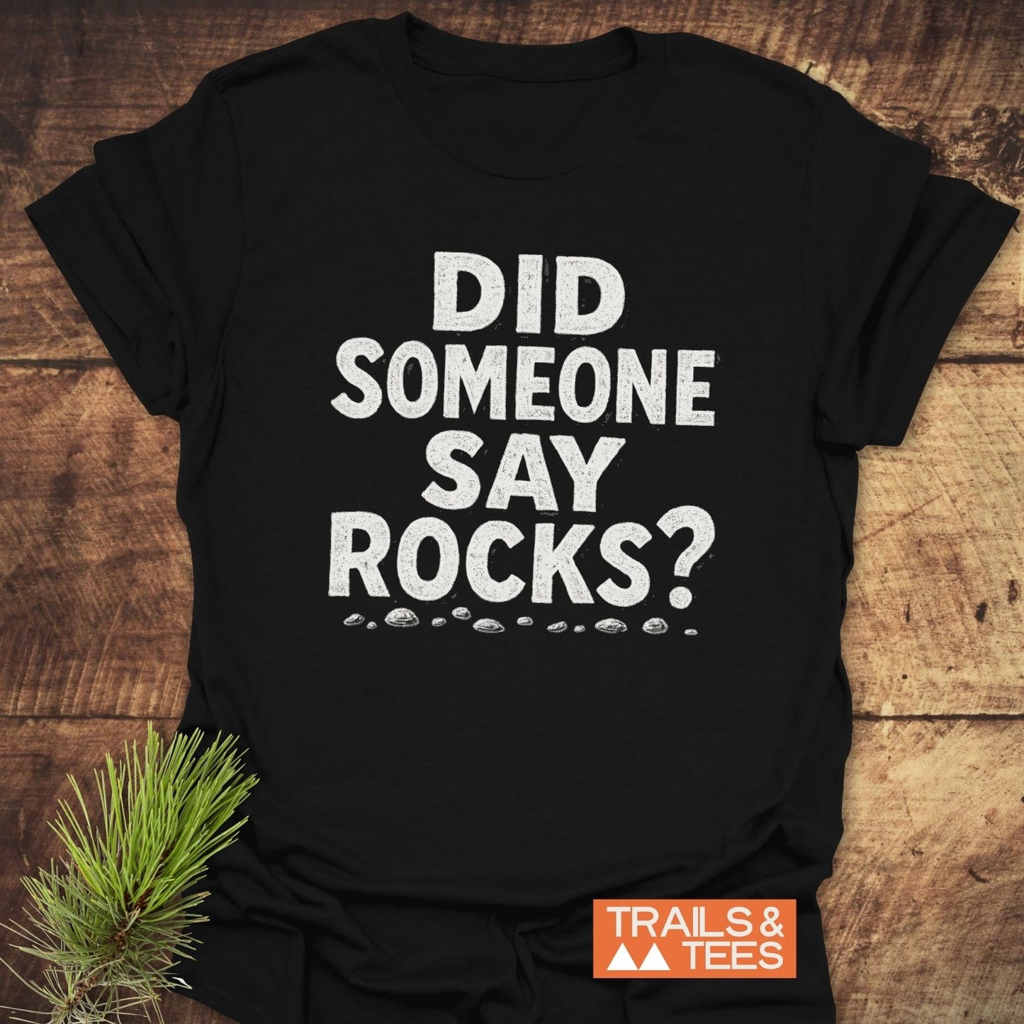 Did Someone Say Rocks? T-Shirt with pebble illustrations, showcasing Trail-tested comfort in soft, lightweight cotton, ideal for outdoor enthusiasts. Includes Trails & Tees logo.