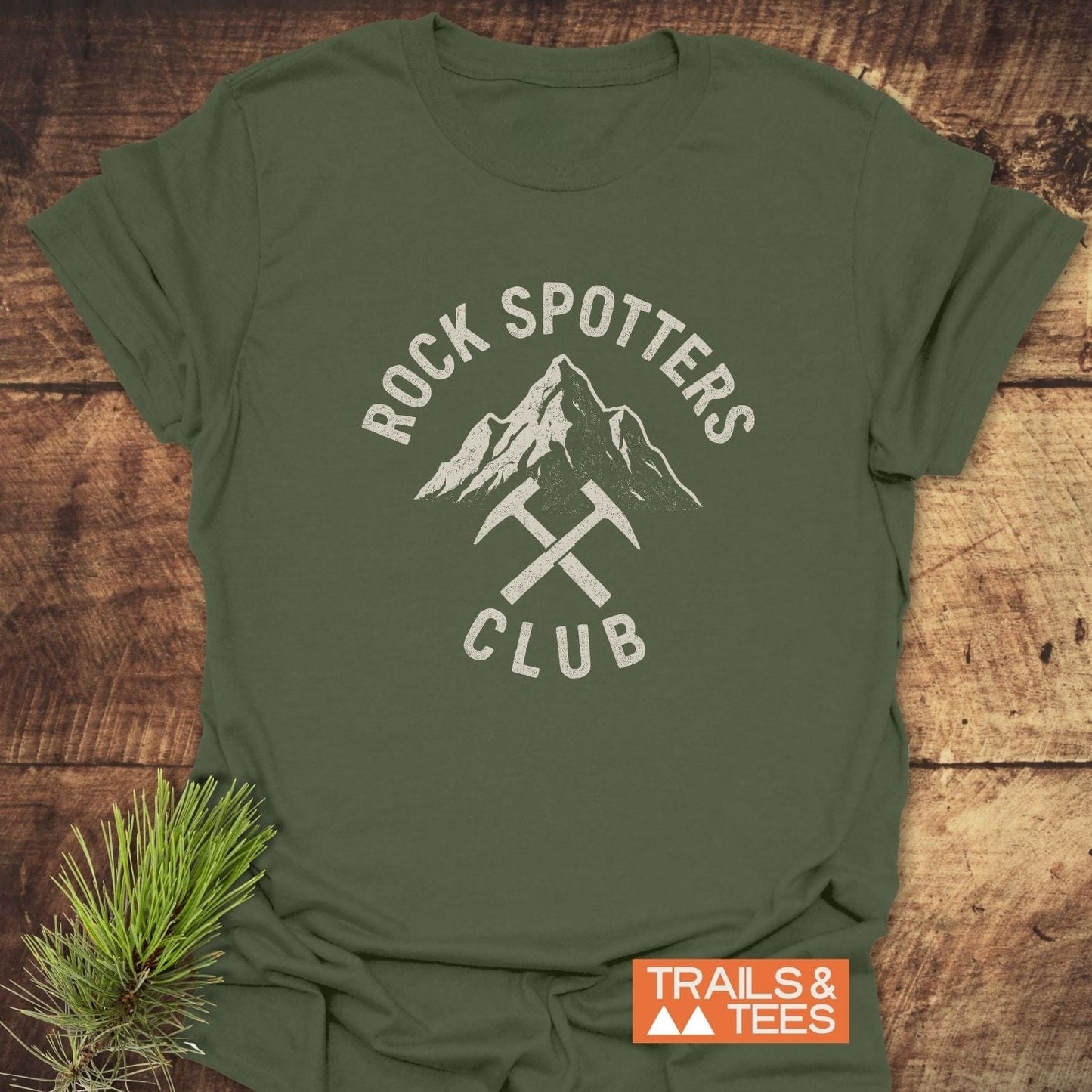 Rock Spotters Club T-Shirt featuring a mountain peak and rock-hammers graphic, crafted from soft cotton for comfort, perfect for outdoor enthusiasts.