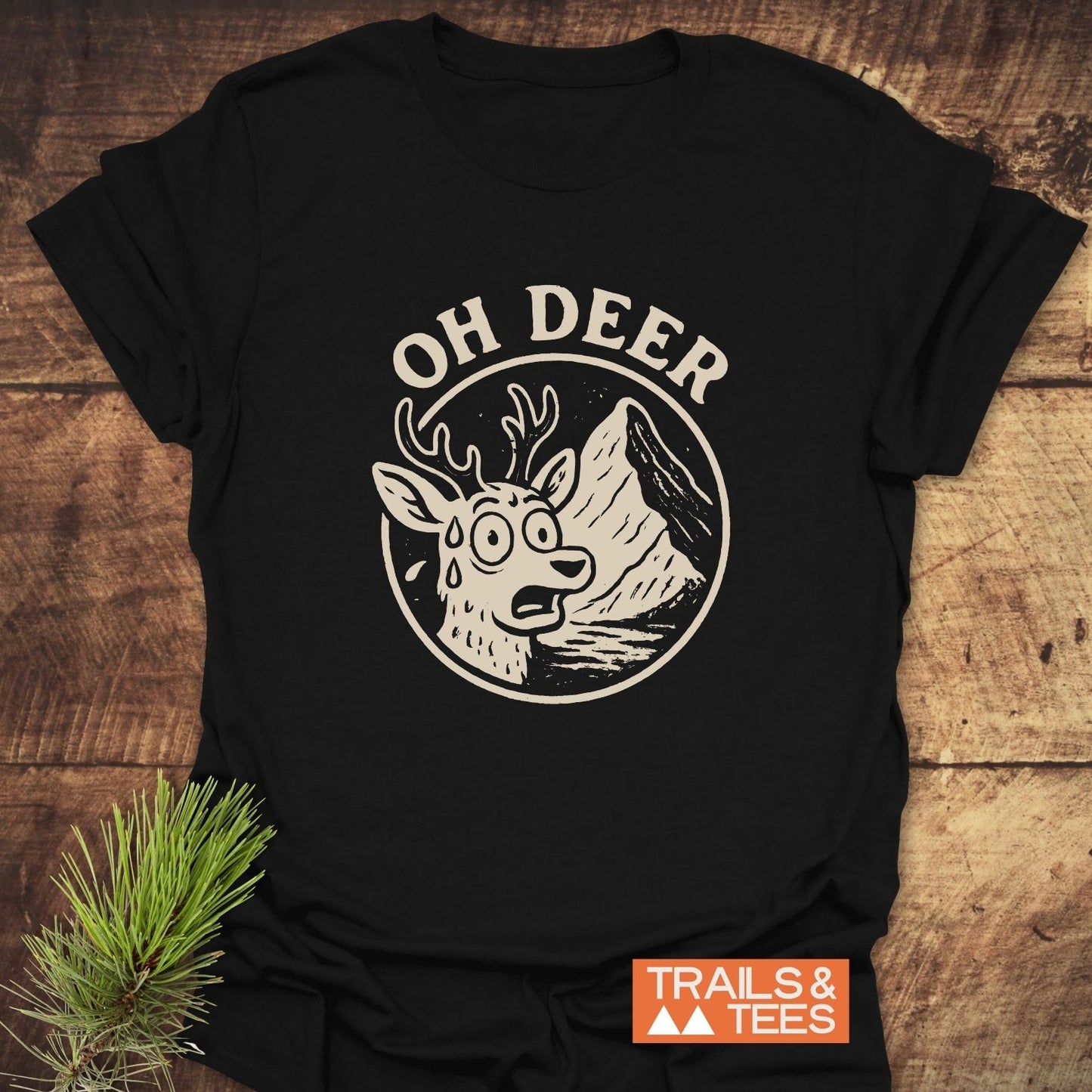 Oh Deer Funny Hiking T-Shirt with a cartoon deer graphic on a rustic surface, highlighting its soft cotton fabric and durable outdoor-themed design.