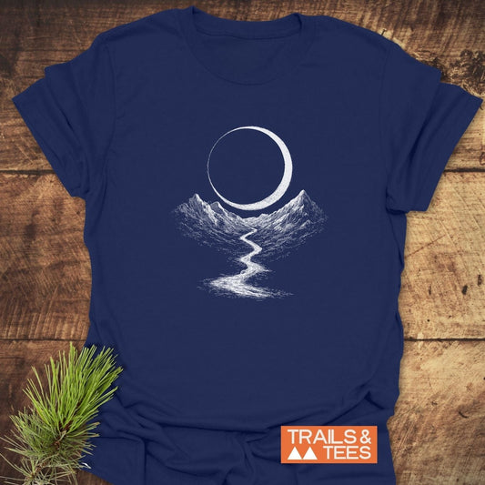 Eclipse Trail T-Shirt featuring a white mountain landscape and crescent moon design, with TRAILS & TEES logo, on a soft, ring-spun cotton fabric.