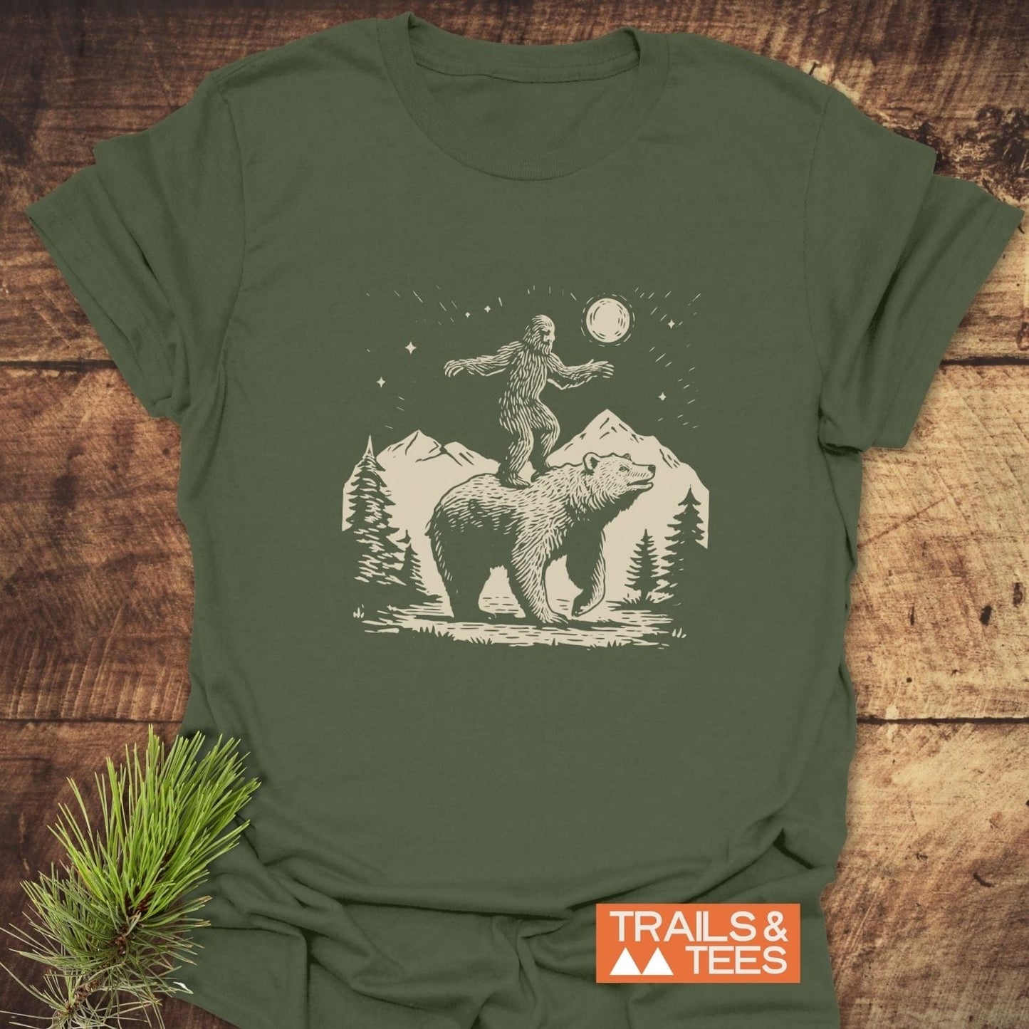Bigfoot And Bear Funny T-Shirt featuring a bear and Bigfoot under a night sky, showcasing durable DTF prints and soft, pre-shrunk cotton for adventure wear.