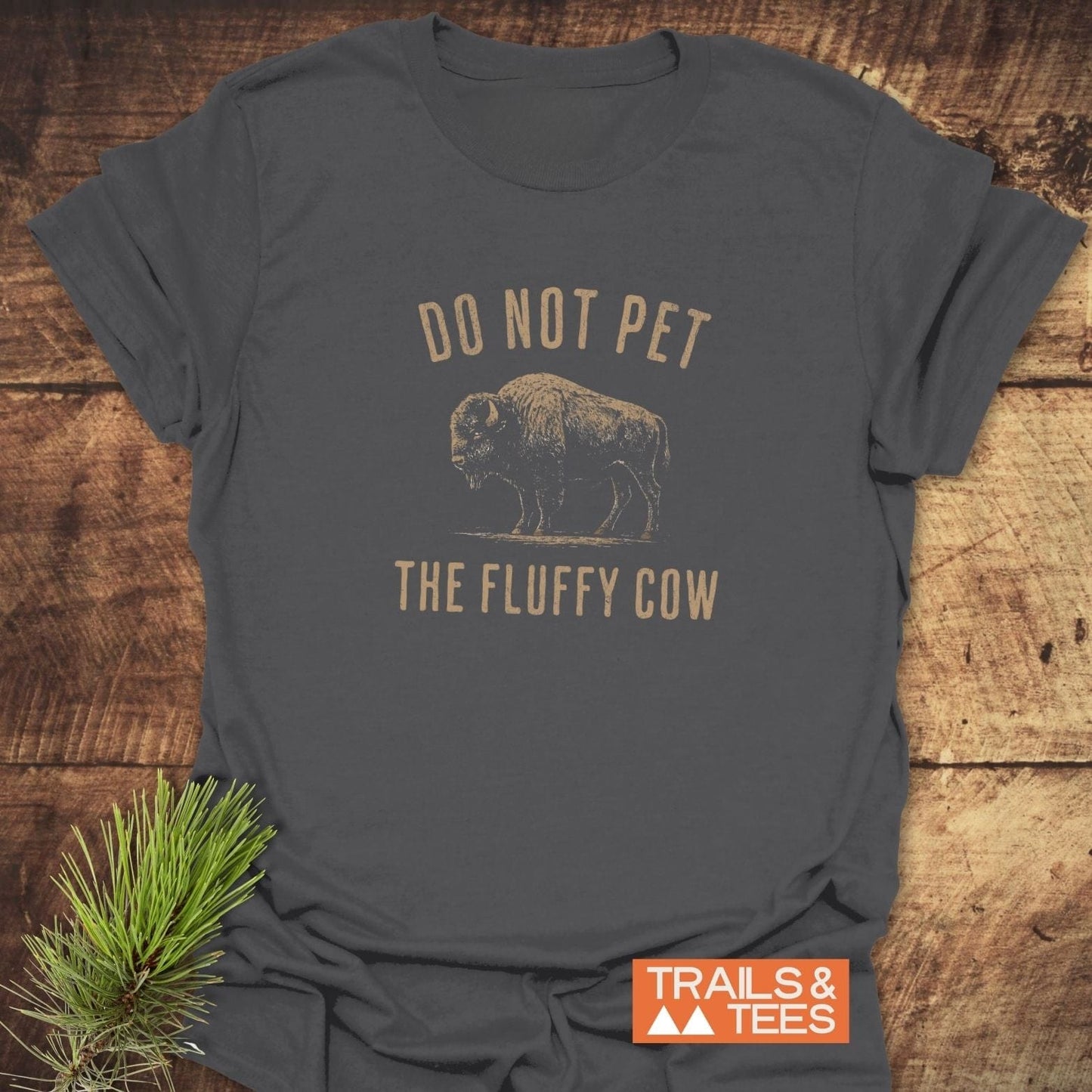 Charcoal-gray Do Not Pet Bison T-shirt with bison sketch, laid on wood. Features soft, durable cotton, designed for outdoor enthusiasts by Trails & Tees.