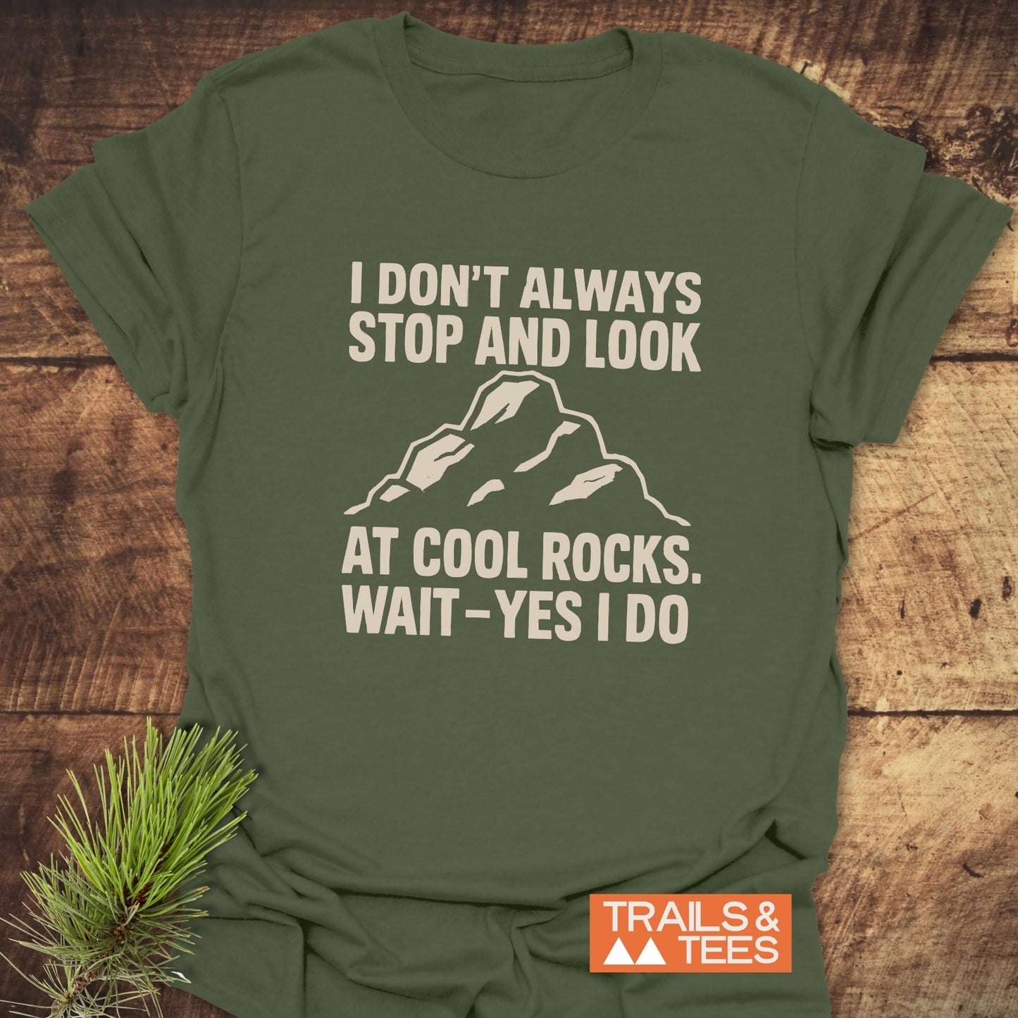 Olive-green I Don't Always... Rock Lover T-Shirt with cream graphic, orange TRAILS & TEES logo, and pine sprig, showcasing outdoor adventure spirit and comfort.