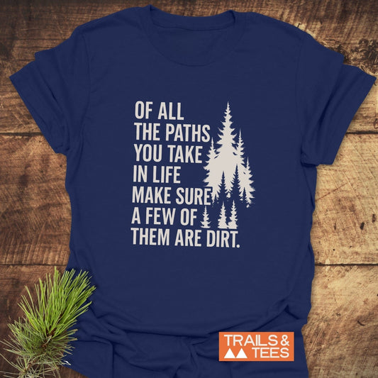 Of All The Paths T-Shirt featuring pine trees and slogan on navy-blue cotton, laid on wood with Trails & Tees logo and a pine sprig.