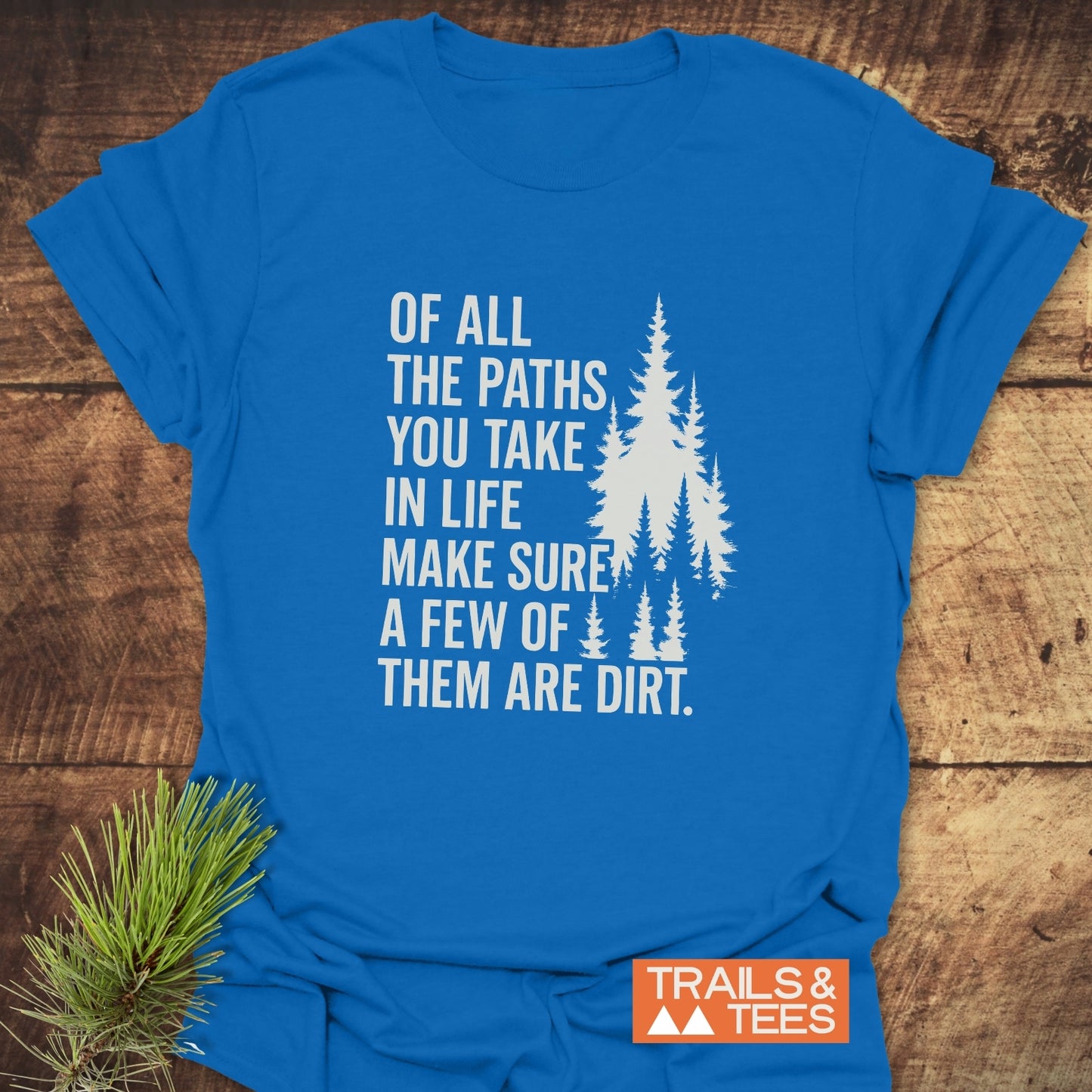 Of All The Paths T-Shirt; bright blue with white pine tree graphic and quote, featuring TRAILS & TEES logo. Soft cotton, durable print, adventure-ready.