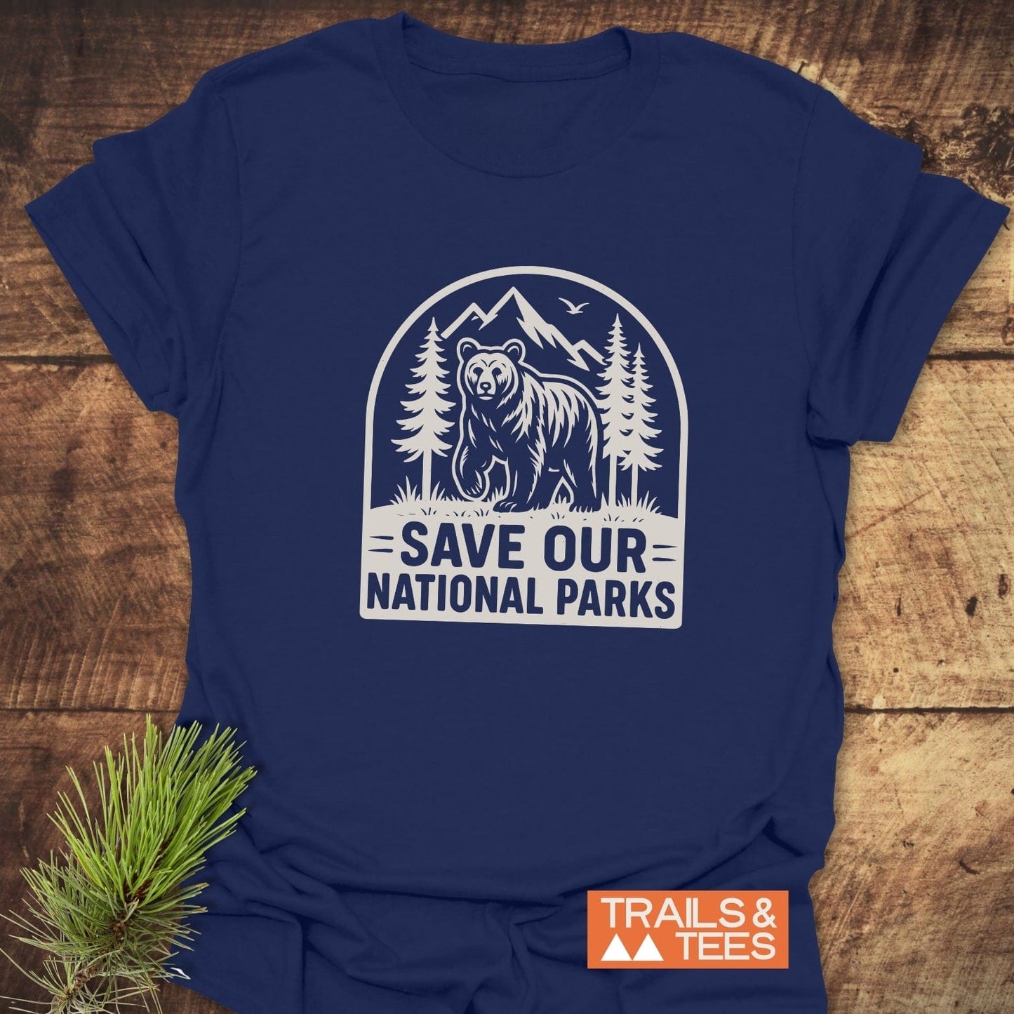 Save National Parks T-Shirt with bear and pine graphic on navy fabric, laid flat. Features durable print and soft cotton for everyday outdoor adventures.