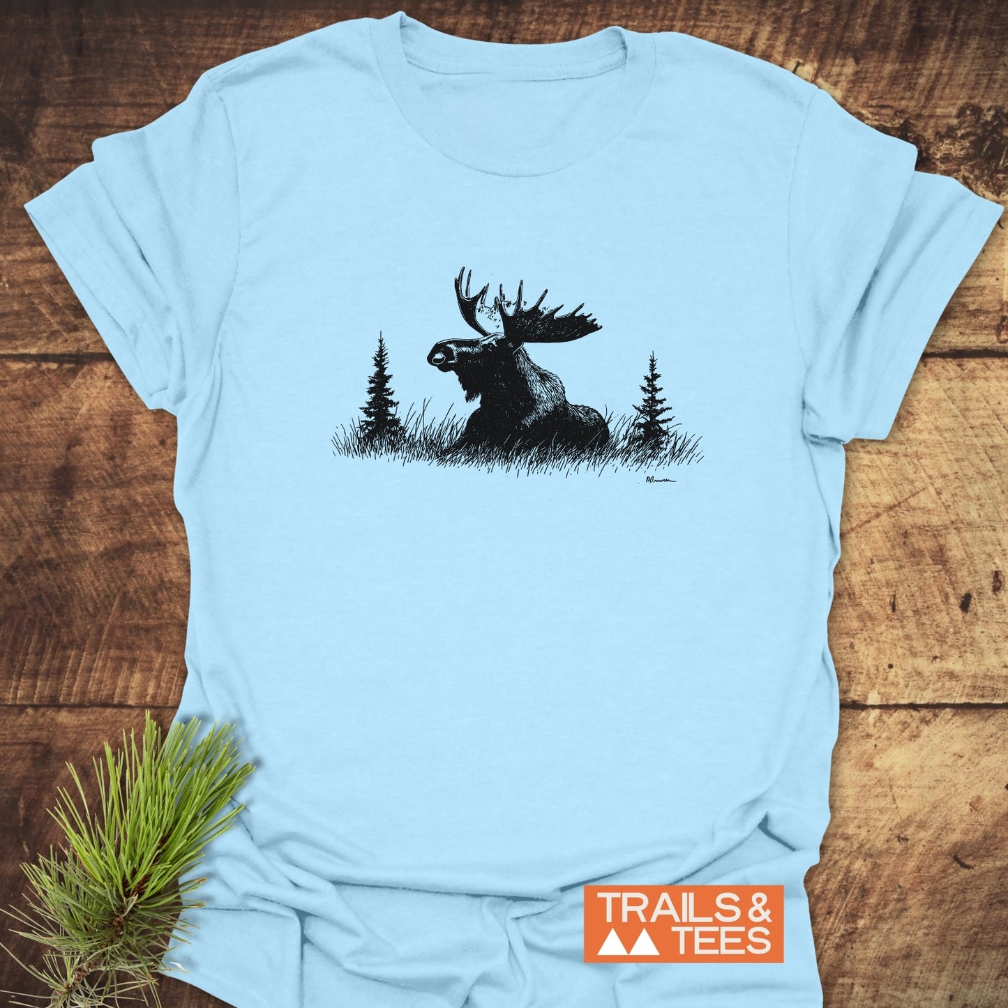 Relaxing Moose T-Shirt featuring a bull moose graphic with pine trees on a light-blue tee, showcasing soft cotton comfort and durable print.