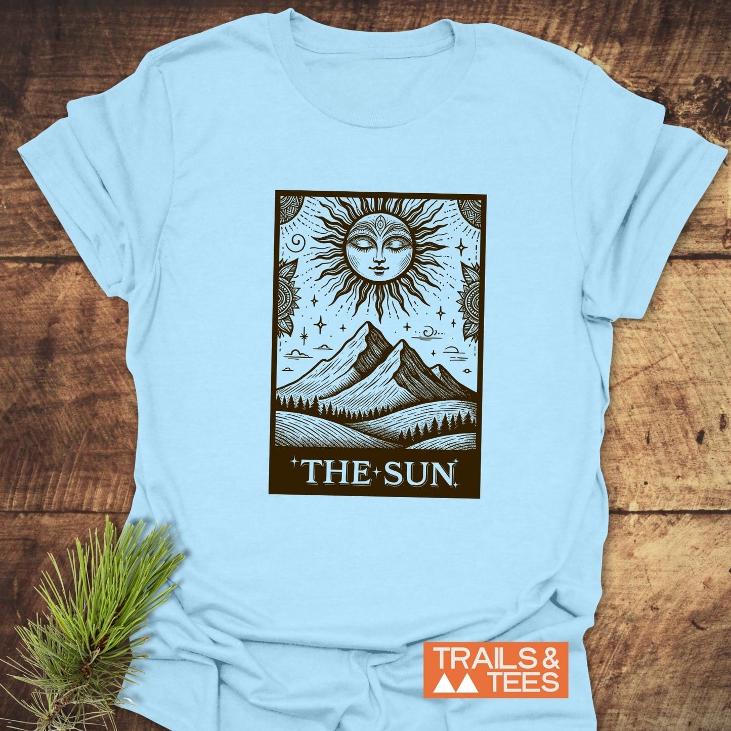 The Sun Tarot T-Shirt features a tarot-style sun graphic with mountains and trees, embodying outdoor adventure. Crafted from soft cotton for comfort and durability.