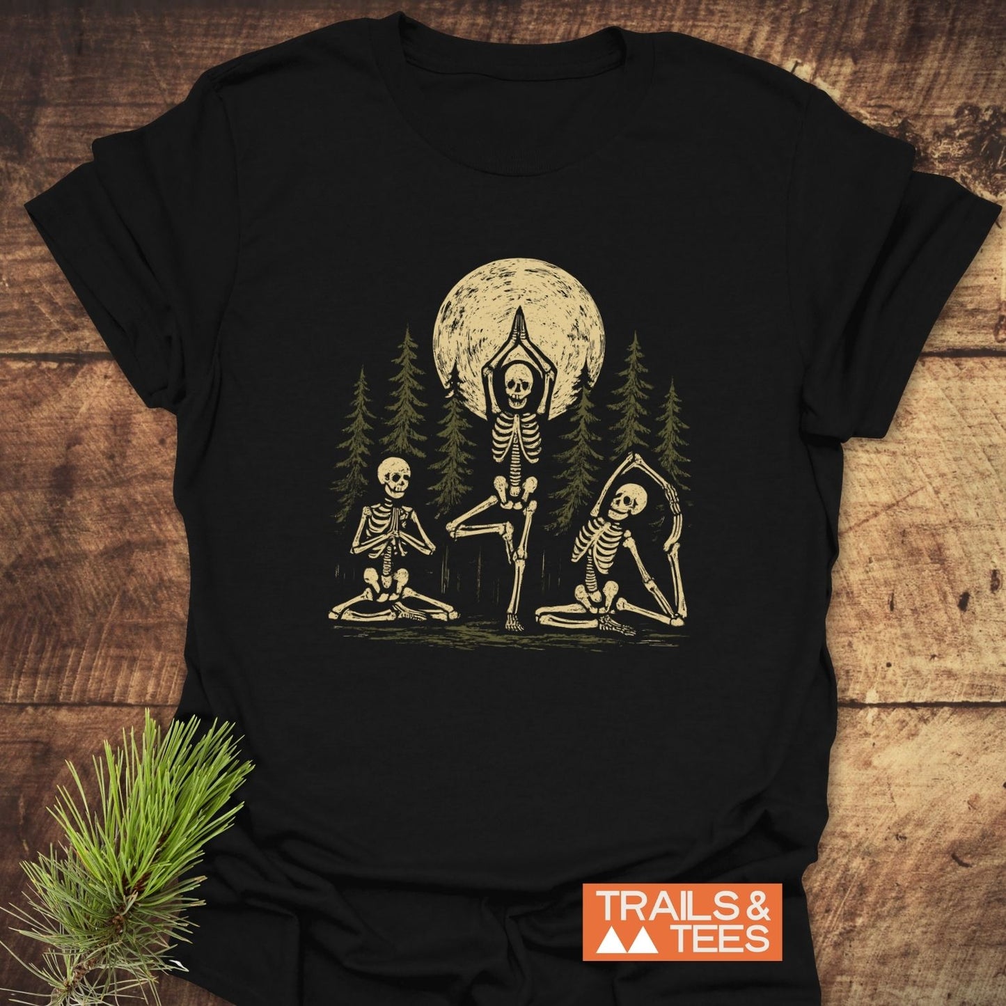 Relax In The Woods T-Shirt featuring skeletons in yoga poses with pine trees and a full moon; crafted from soft, lightweight cotton for trail-tested comfort.