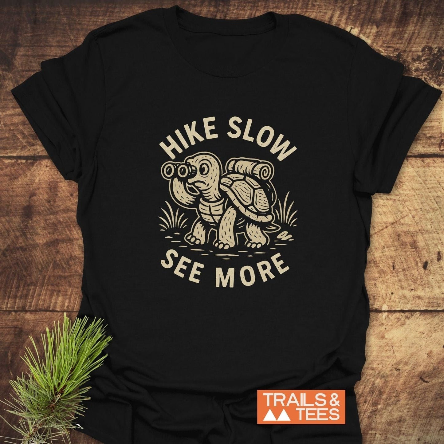 Black T-shirt with HIKE SLOW, SEE MORE around a turtle graphic. Lightweight, durable, and pre-shrunk, ideal for outdoor enthusiasts.