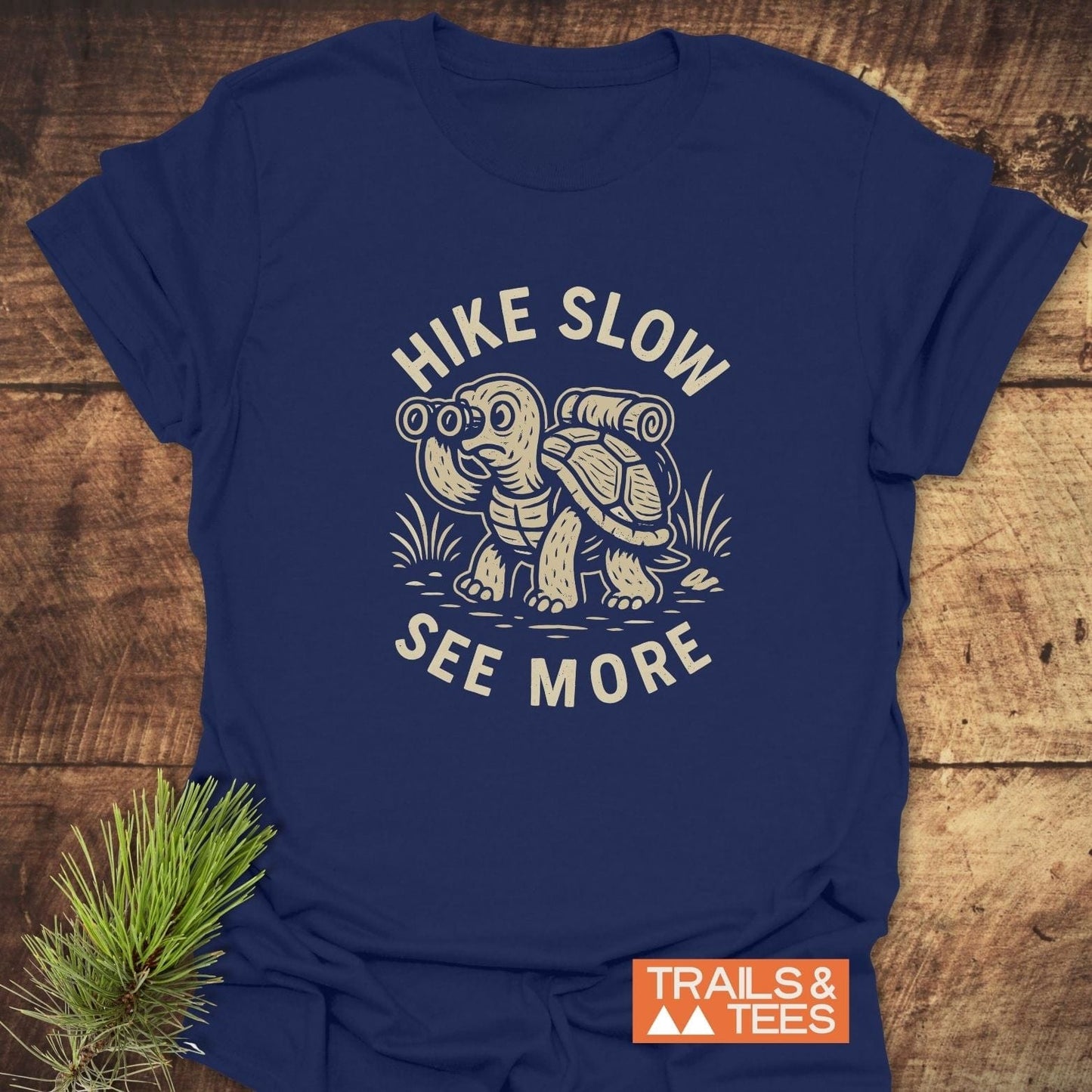Navy-blue Hike Slow Funny T-Shirt with a hiking tortoise design, slogan, and Trails & Tees logo, crafted from soft, durable cotton for outdoor enthusiasts.