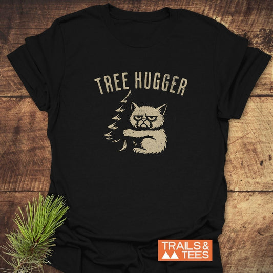 Tree Hugger Funny T-Shirt featuring a grumpy cat hugging a pine tree graphic. Made from soft, lightweight cotton, it offers comfort and durability for outdoor lovers.
