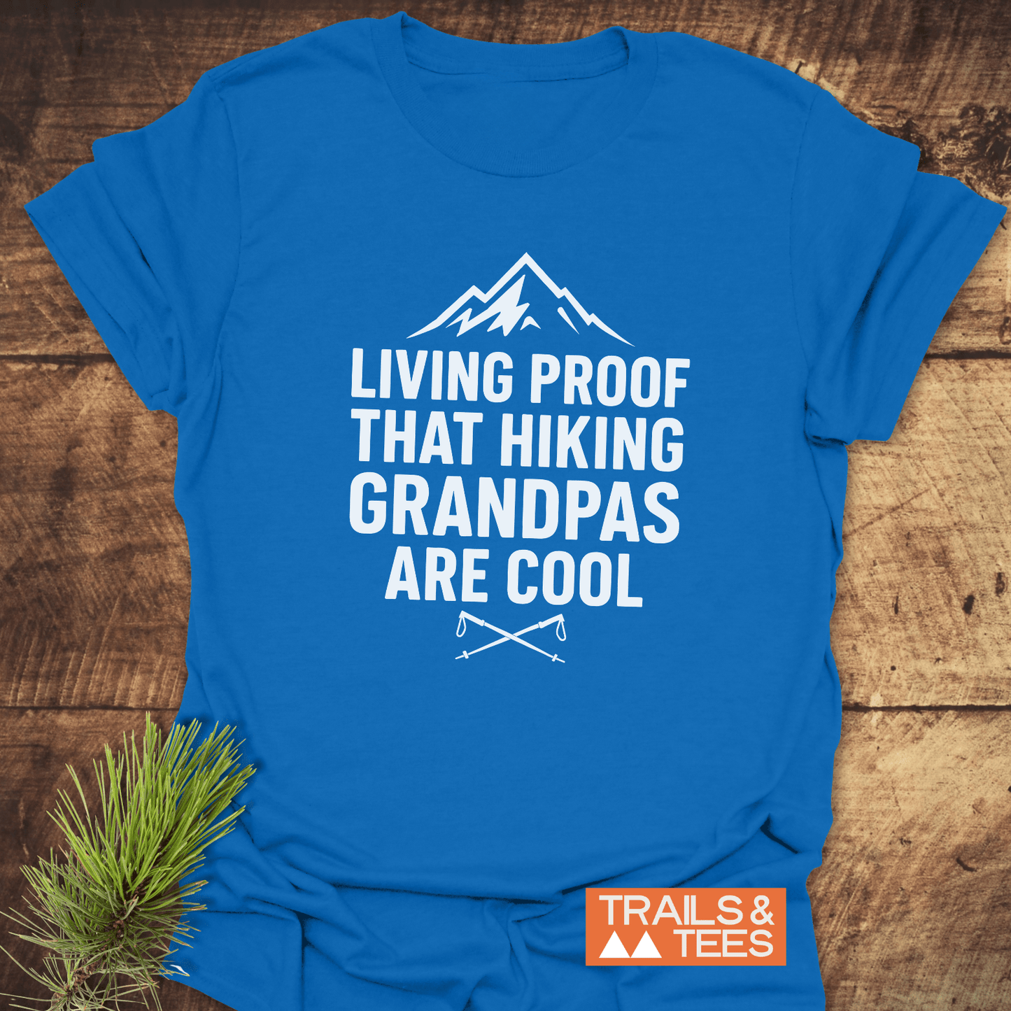 606 Living Proof Grandpa T-Shirt featuring a mountain graphic and text, laid on wood. Soft, durable cotton, ideal for outdoor-loving grandpas.