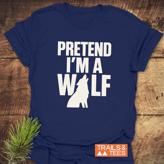 Navy blue Pretend I'm A Wolf T-shirt with a wolf silhouette, on rustic wood, featuring Trails & Tees logo. Pine sprig adds a nature vibe.