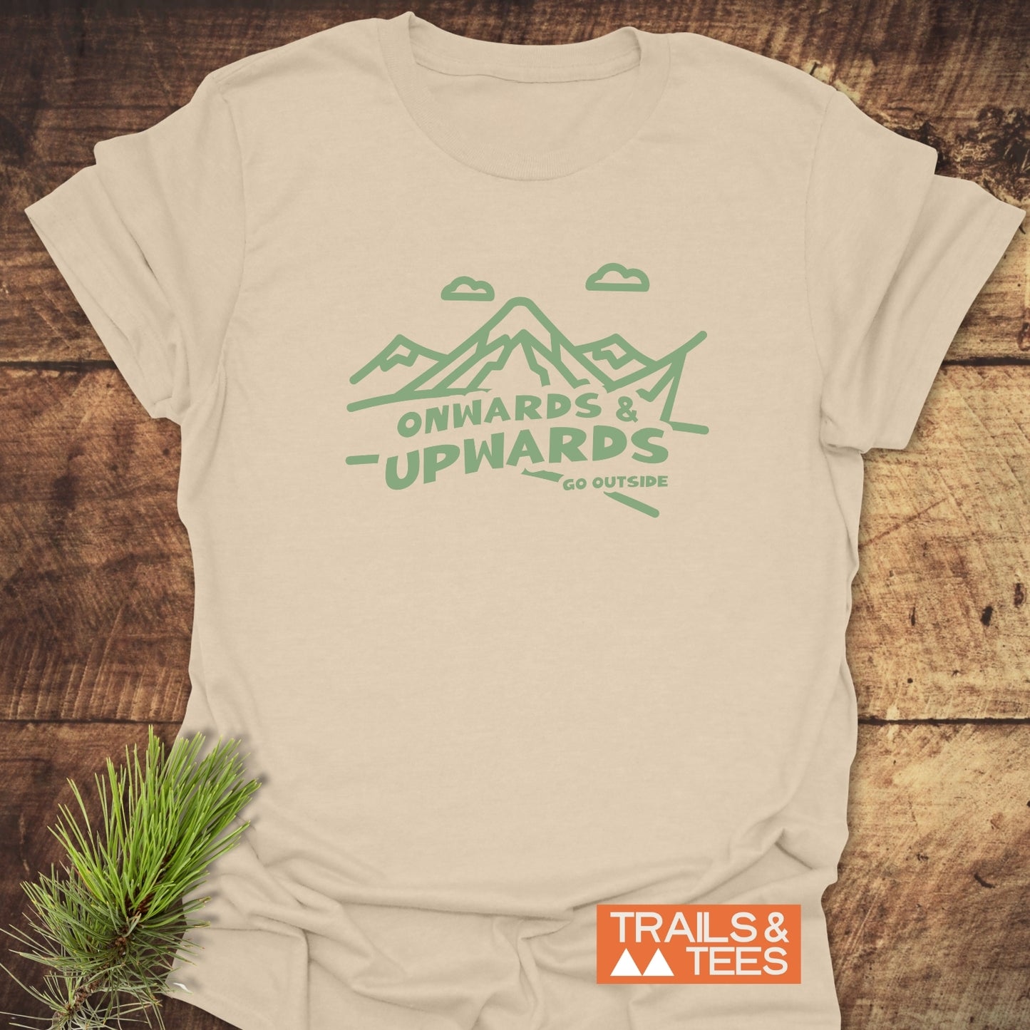 Go Outside T-Shirt featuring mint-green mountain graphic, “ONWARDS & UPWARDS” slogan, laid on wood. Soft ring-spun cotton for comfort and durability.