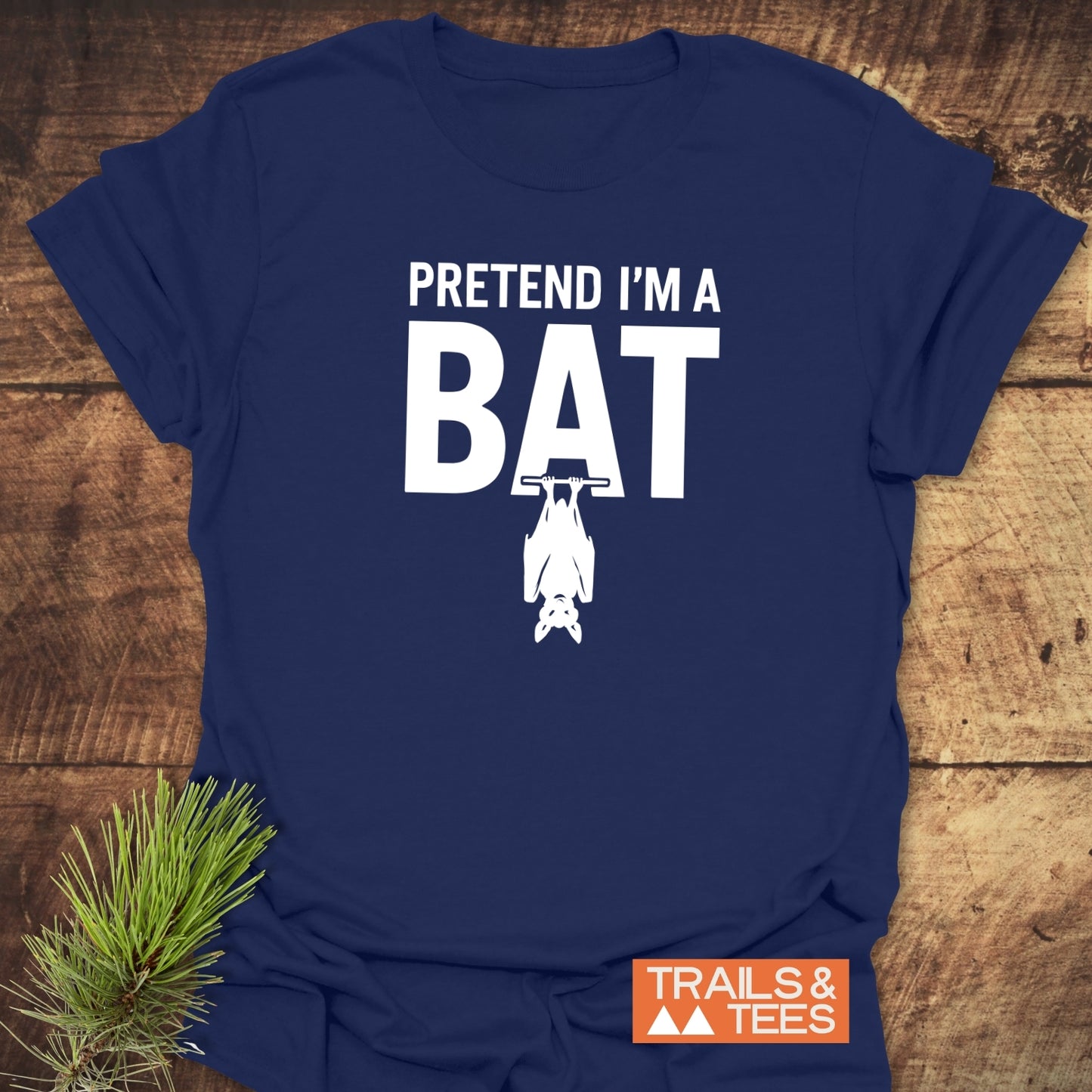 I'm A Bat T-Shirt with bold 'BAT' design and upside-down bat silhouette, laid on wood. Soft, ring-spun cotton for comfort, outdoor-inspired.