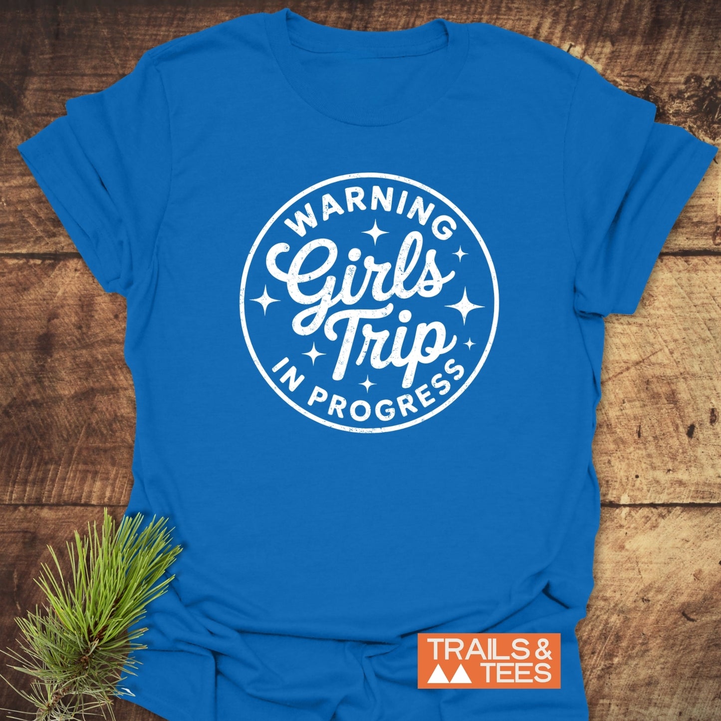 Girls Trip Hiking T-Shirt featuring a white stamp-style graphic on blue fabric, laid on wood. Durable, lightweight cotton, pre-shrunk, and printed on demand.