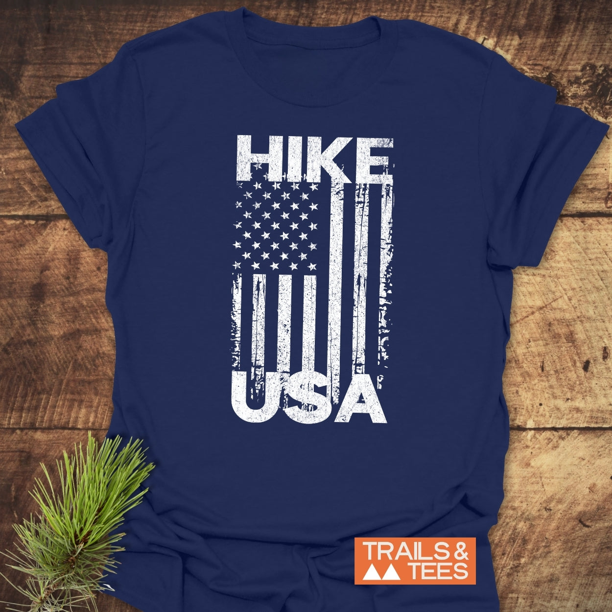 Navy-blue Hike USA T-shirt with distressed white graphic, showcasing American flag design. Features soft ring-spun cotton, durable prints, and TRAILS & TEES logo tag.