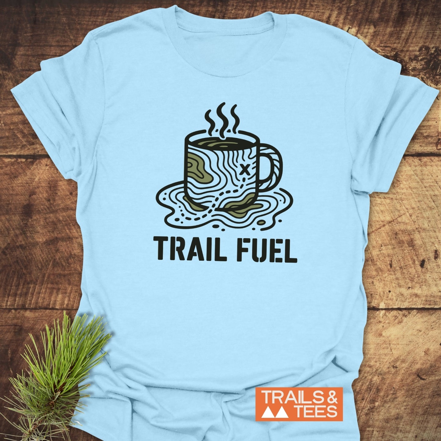 Trail Fuel T-Shirt featuring a contour-map coffee mug graphic and TRAIL FUEL slogan, laid flat. Made of soft, lightweight cotton, ideal for outdoor enthusiasts.