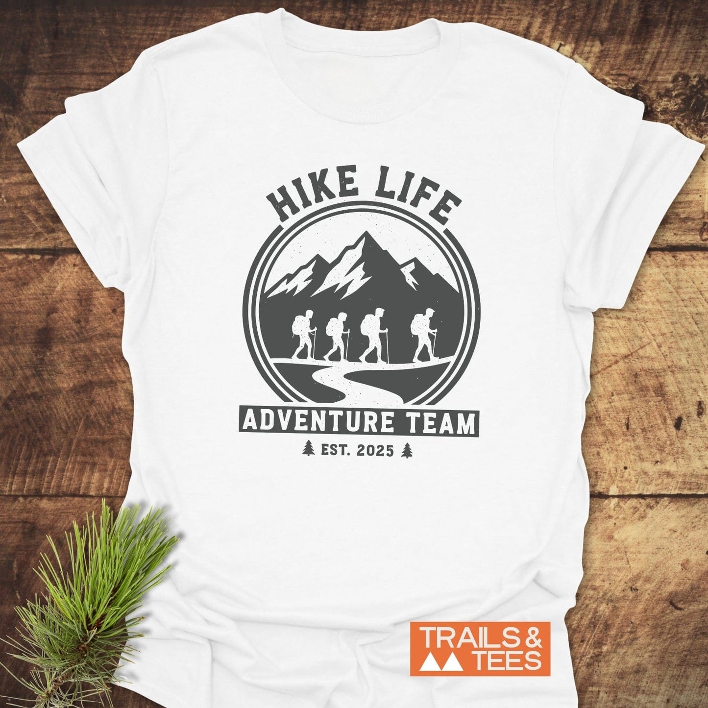 Adventure Team T-Shirt featuring a mountain range graphic with hikers, HIKE LIFE slogan, and TRAILS & TEES logo; crafted from soft ring-spun cotton.