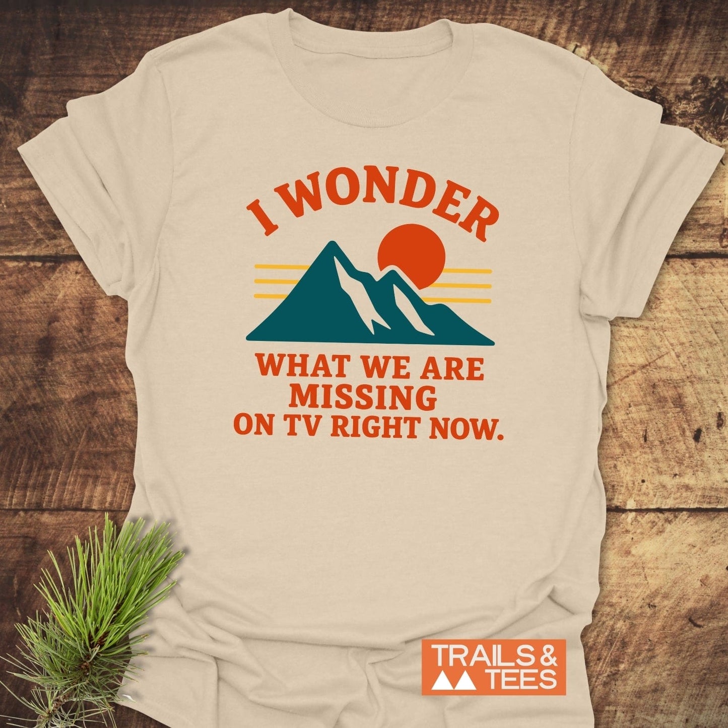 What's On TV Funny T-Shirt featuring teal mountains, a red-orange sun, and bold text. Crafted from soft cotton for outdoor enthusiasts, emphasizing comfort and adventure.