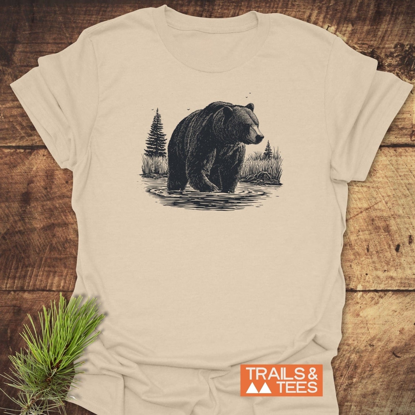 Majestic Grizzly T-Shirt featuring a bear line-art in nature, laid on wood with pine sprig. Soft, ring-spun cotton, durable print, pre-shrunk fit.