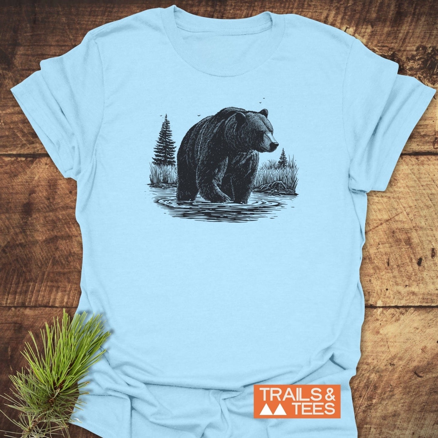 Majestic Grizzly T-Shirt with bear illustration, crafted from soft cotton, featuring durable prints and taped shoulders, styled with a pine branch accent.