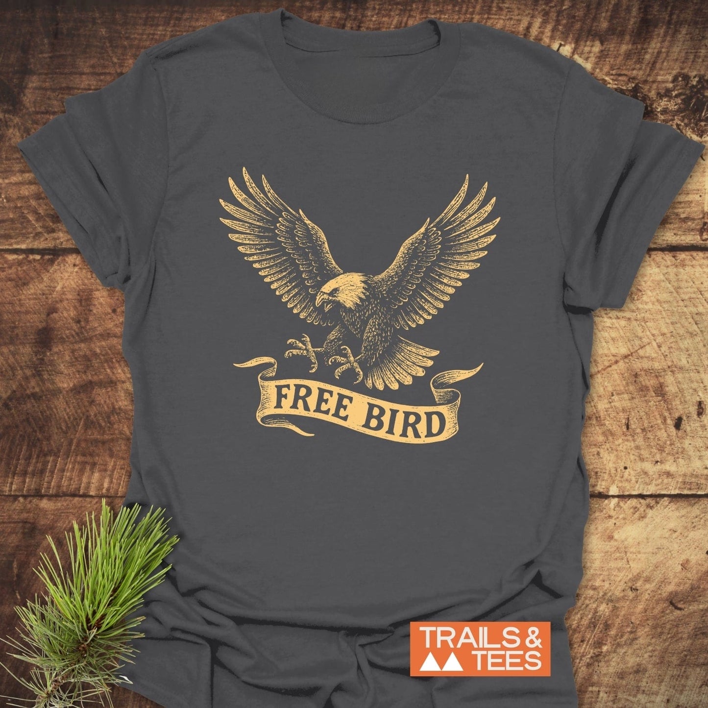 Free Bird T-Shirt featuring a distressed gold eagle print, crafted from soft ring-spun cotton for comfort and durability, styled with a pine sprig.
