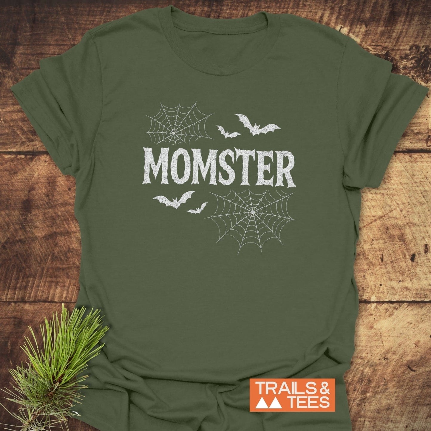 MOMSTER Halloween T-Shirt with spiderwebs and bats on olive-green fabric, showcasing Trails & Tees' durable, lightweight comfort for outdoor adventures.