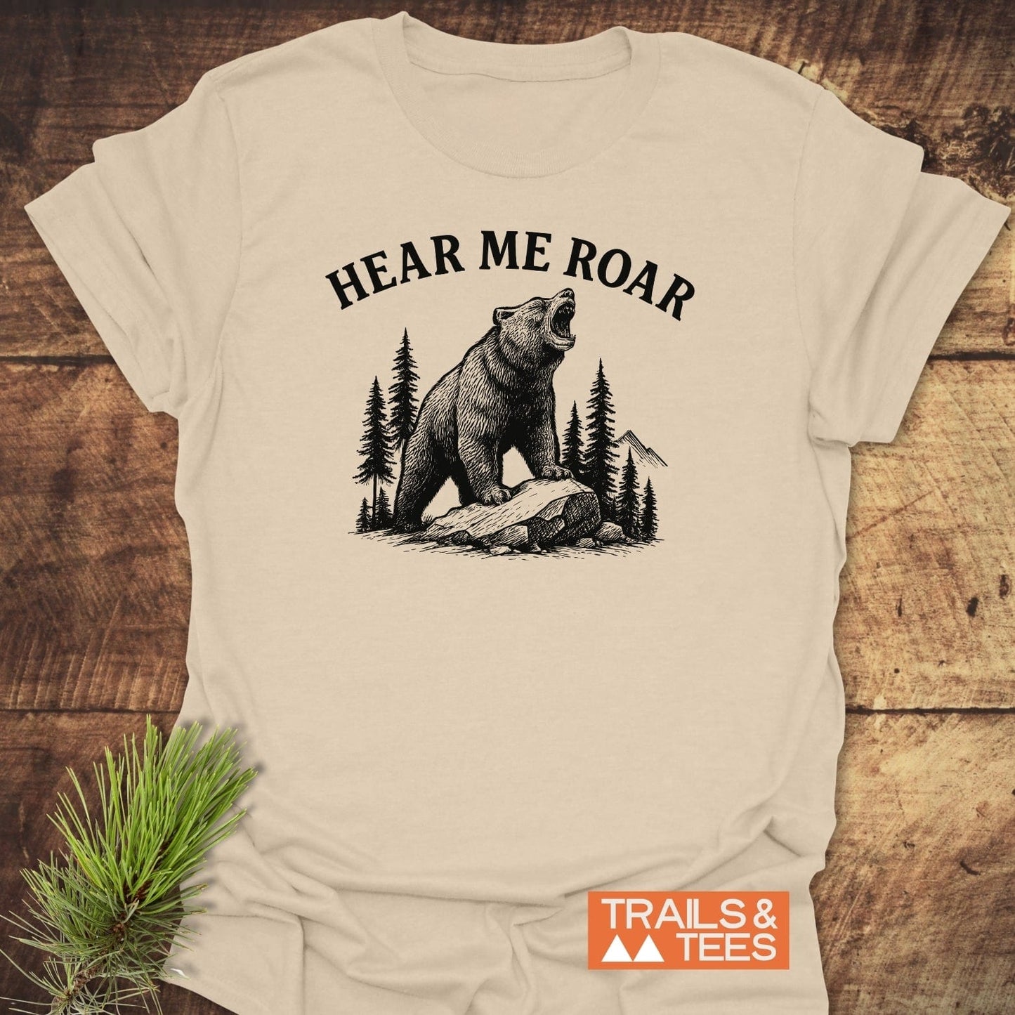 Hear Me Roar T-Shirt featuring a roaring bear graphic with pine trees and mountains, highlighting its outdoor spirit and comfortable, durable design by Trails & Tees.