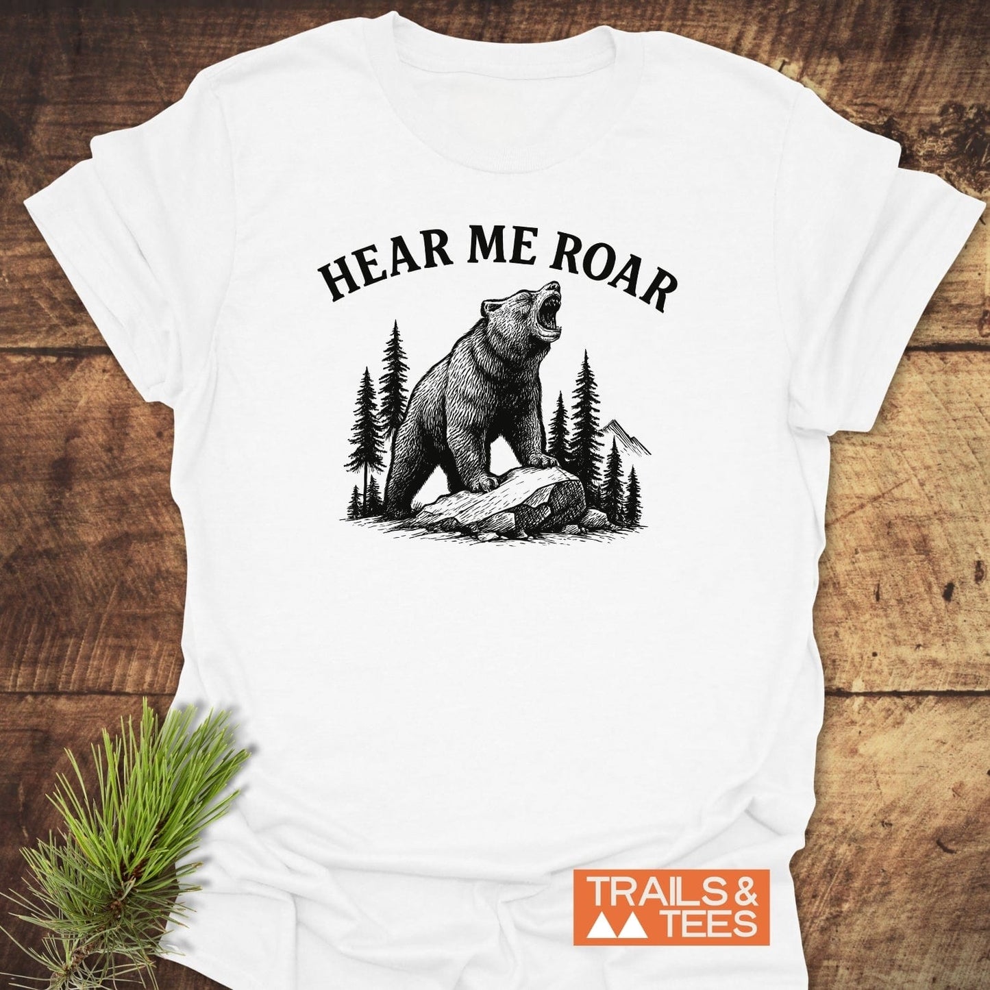 Hear Me Roar T-Shirt featuring a roaring bear design with pine trees and mountains, crafted from soft cotton for comfort and outdoor adventures.