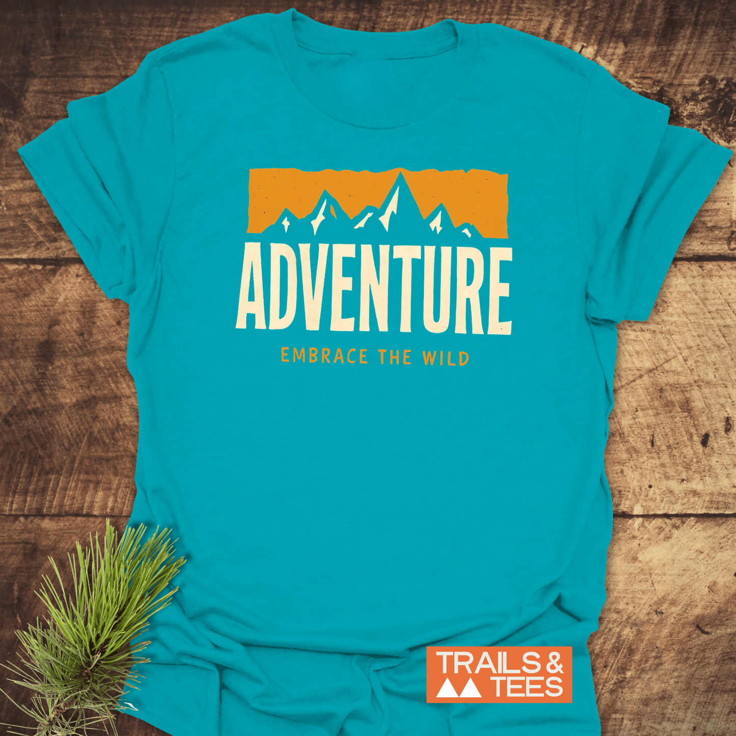 Adventure T-Shirt featuring mountain graphic and “EMBRACE THE WILD” tagline on soft, pre-shrunk cotton, emphasizing comfort and durability for outdoor enthusiasts.