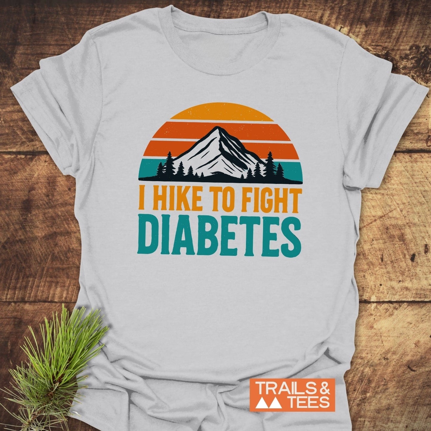 Hike To Fight Diabetes T-Shirt featuring a mountain and sun graphic with pine trees. Made from soft ring-spun cotton for comfort and durability.