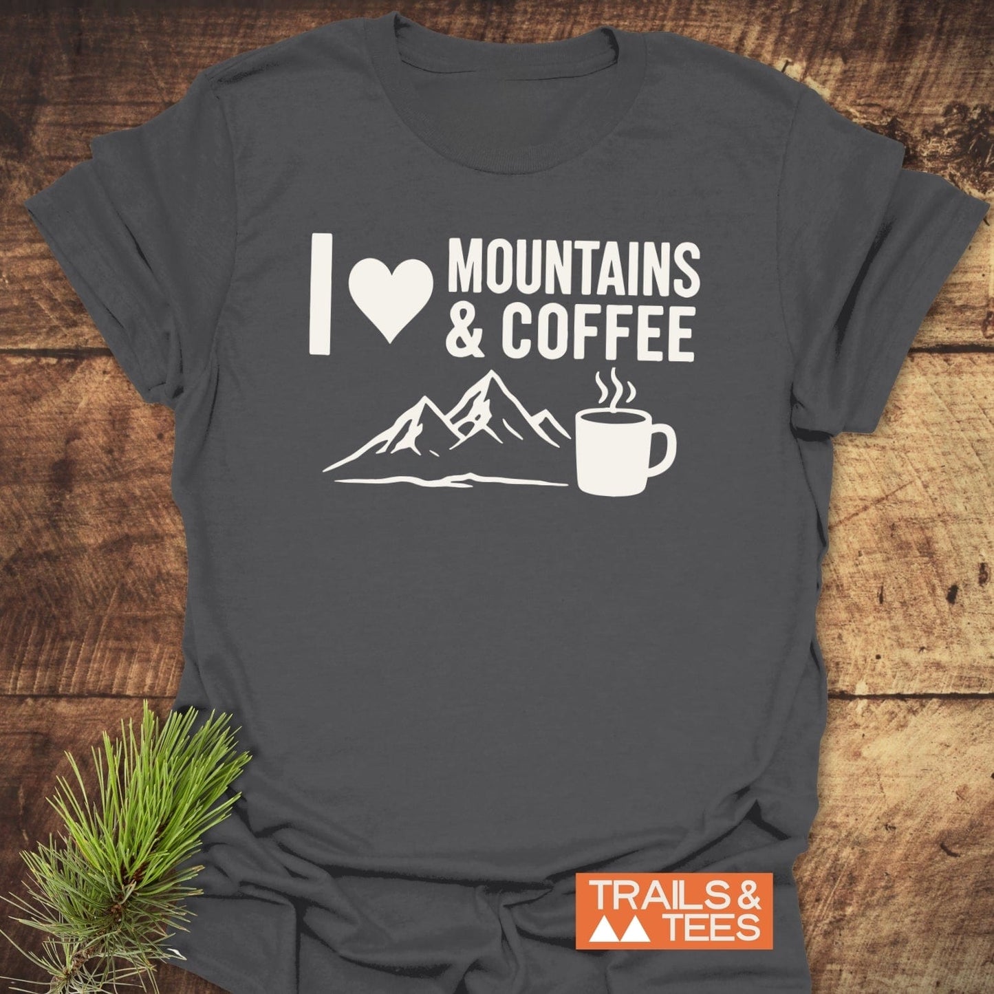 Charcoal-gray I ♥ MOUNTAINS & COFFEE T-shirt with mountain and mug graphic, laid flat, showcasing durable print and soft ring-spun cotton for outdoor enthusiasts.