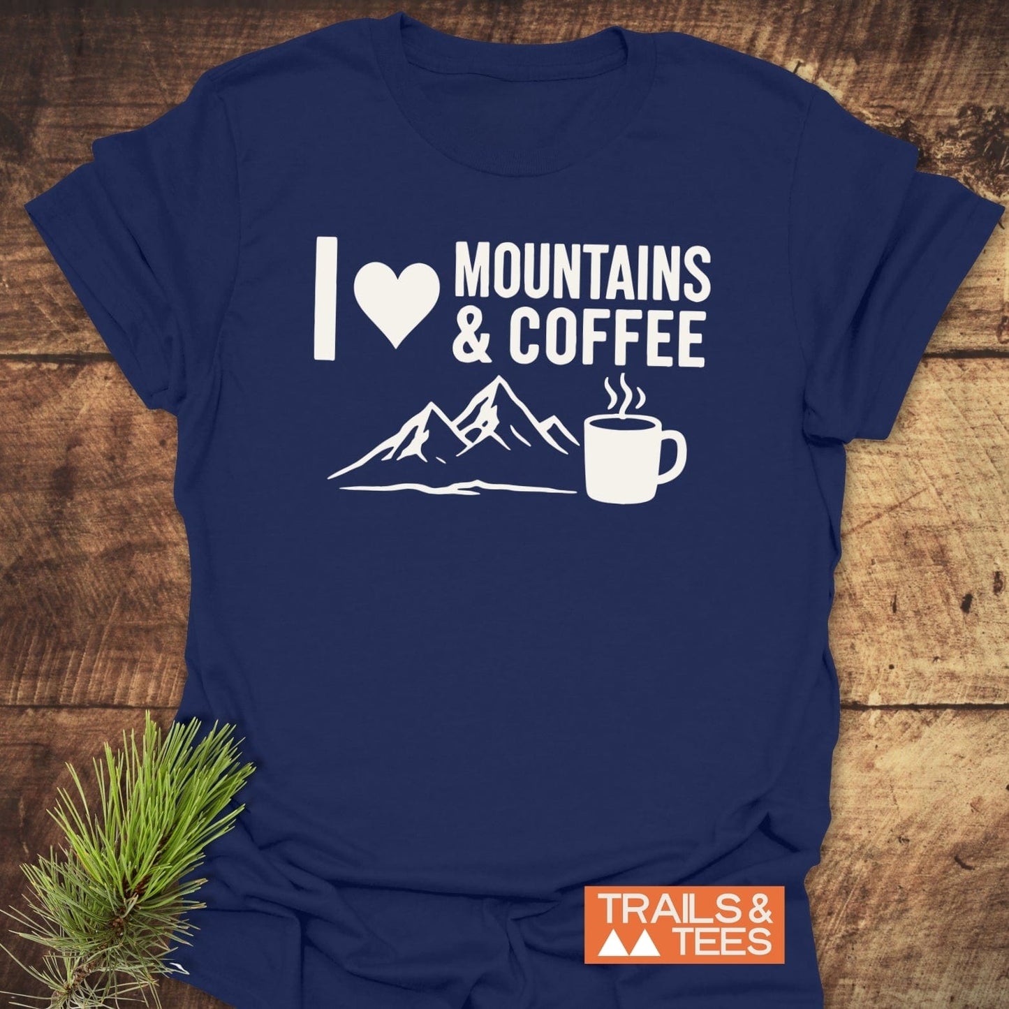 Navy-blue I ♥ Mountains & Coffee T-shirt with mountain and coffee graphic, laid flat on wood; features durable, soft cotton, pre-shrunk for a reliable fit.