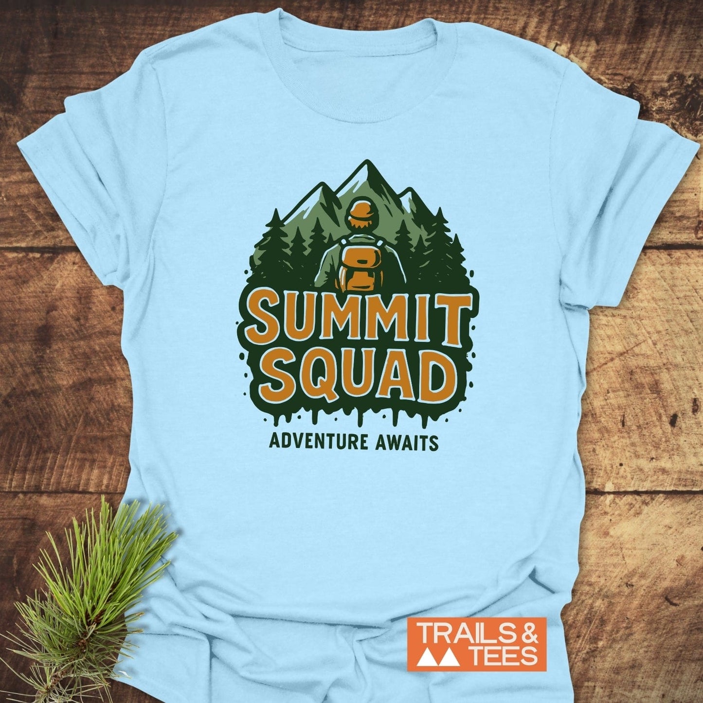 Summit Squad Hiking T-Shirt featuring a hiker graphic with “ADVENTURE AWAITS” text. Made from soft cotton, ensuring comfort and durability. Brand: TRAILS & TEES.