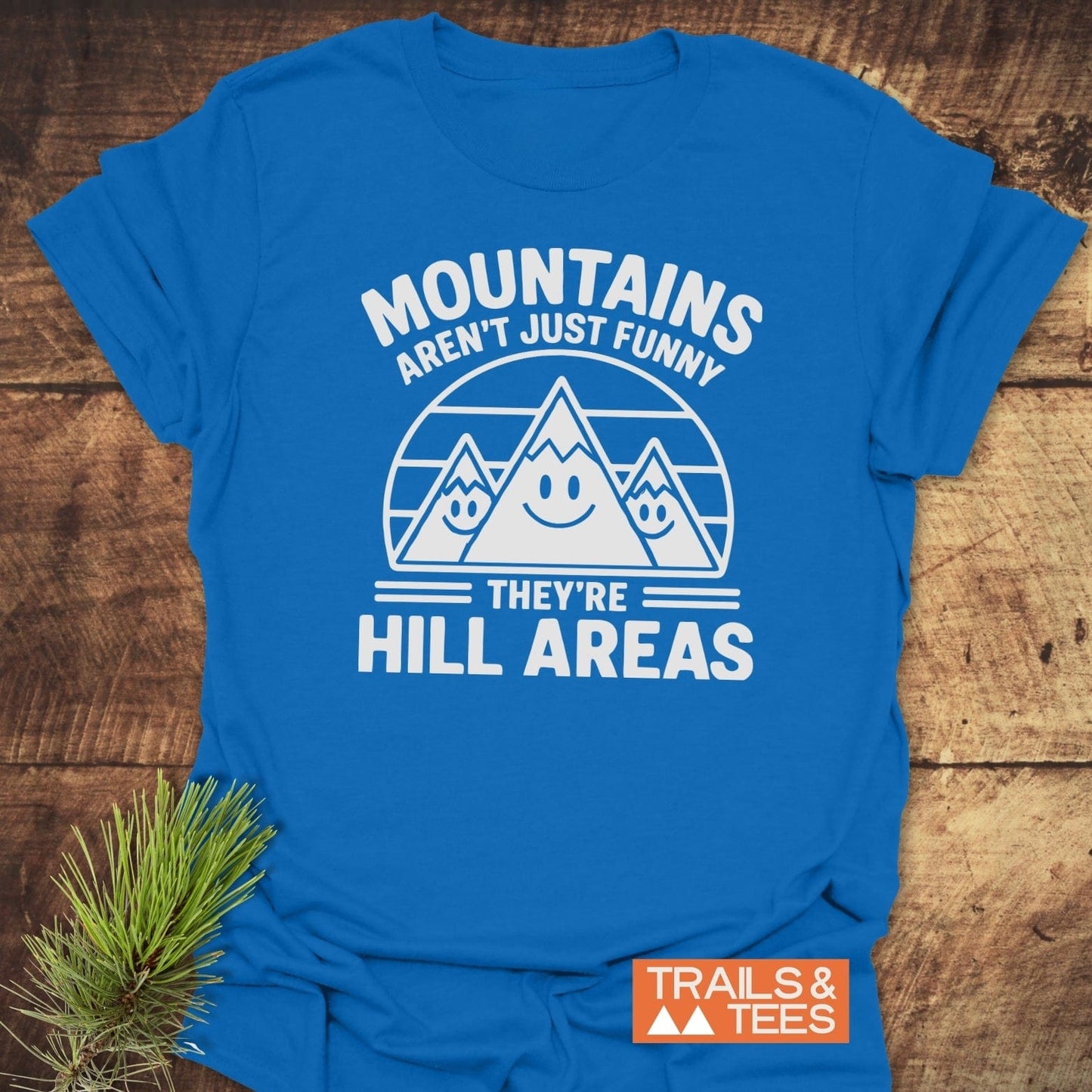 Copy of I love Mountains And Coffee T-Shirt featuring cartoon mountain peaks with a humorous quote, durable print, and Trails & Tees logo on lightweight cotton.