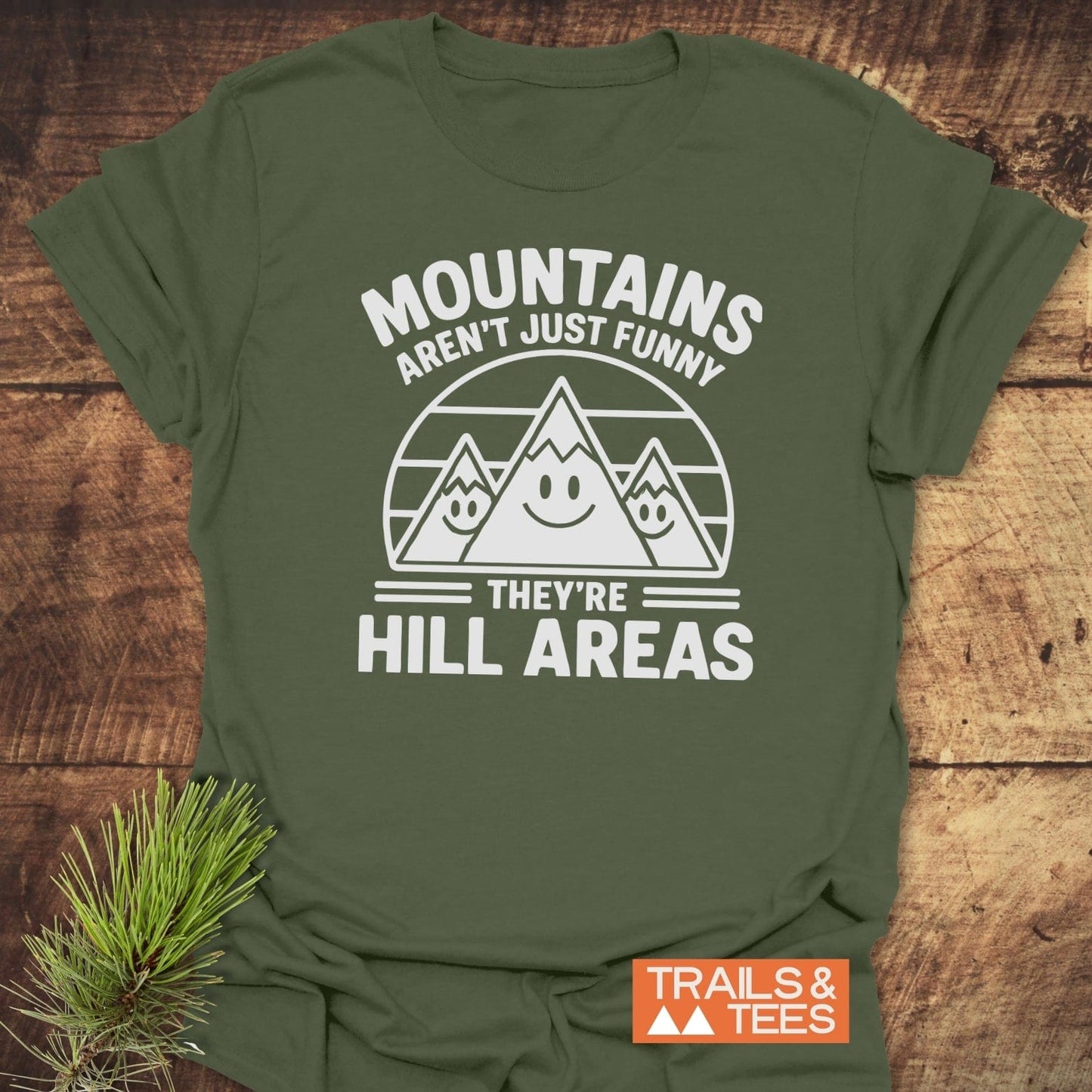 Copy of I Love Mountains And Coffee T-Shirt with cartoon mountains and slogan, styled with pine branch, showcasing soft, durable cotton for outdoor adventures.