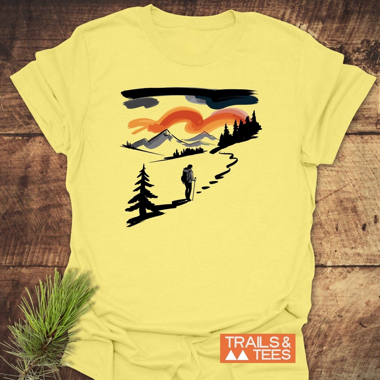 Minimalist Ink Hiking T-Shirt featuring a hiker scene on pale yellow cotton, emphasizing outdoor adventure and comfort. Includes TRAILS & TEES logo, designed for durability.