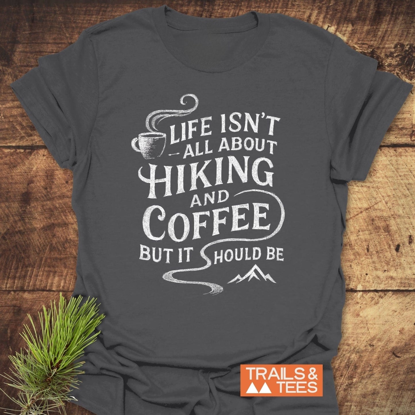 Charcoal-gray Hiking and Coffee T-Shirt featuring a white coffee cup and mountain design, emphasizing comfort and adventure. Includes Trails & Tees logo.