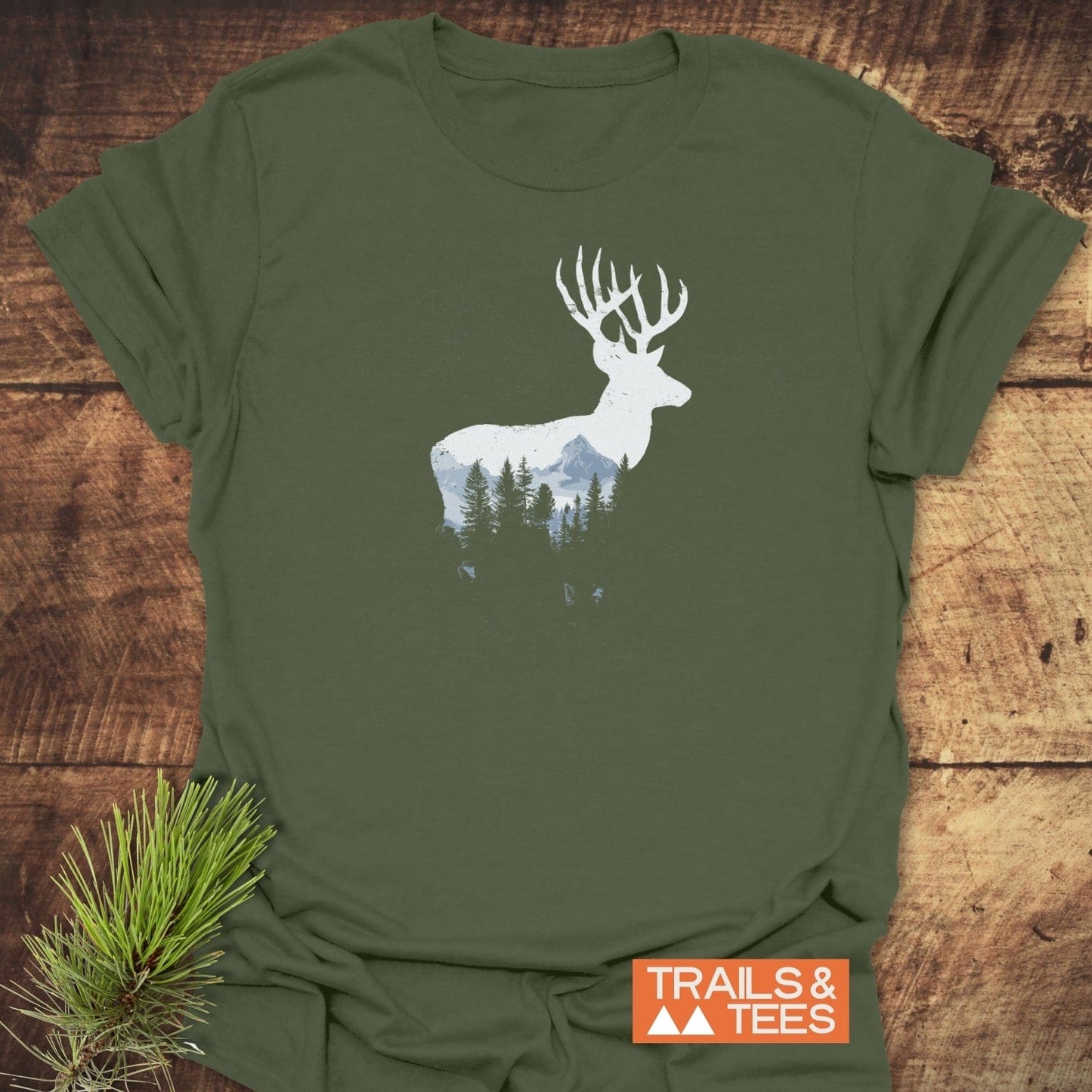 Deer Silhouette T-Shirt: Olive-green tee with a stag and mountain-forest design, lightweight cotton for comfort, featuring durable prints and eco-friendly production by TRAILS & TEES.