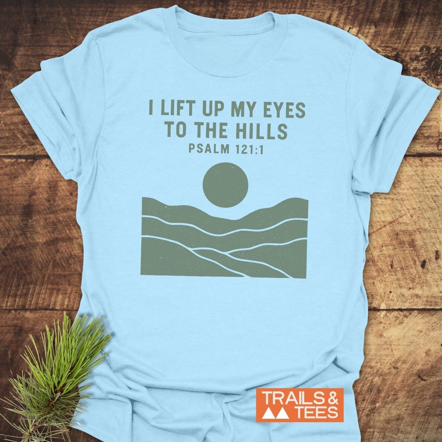 Light-blue I Lift My Eyes Mountain T-Shirt with Psalm 121:1 text and minimalist hills graphic, featuring durable design and soft ring-spun cotton for outdoor adventures.