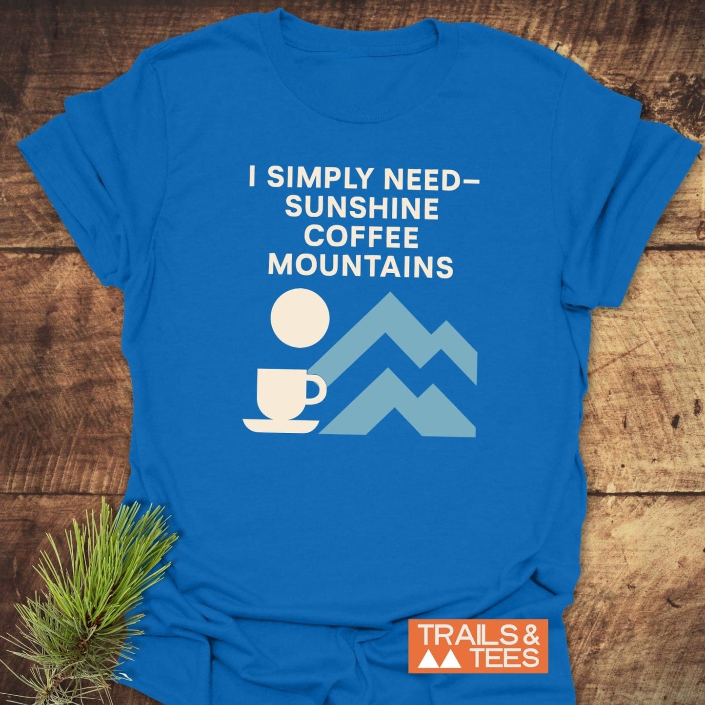Geometric Mountain Love T-Shirt featuring a white motto, coffee cup, sun, and mountains on bright blue fabric, showcasing Trails & Tees' outdoor-inspired design.