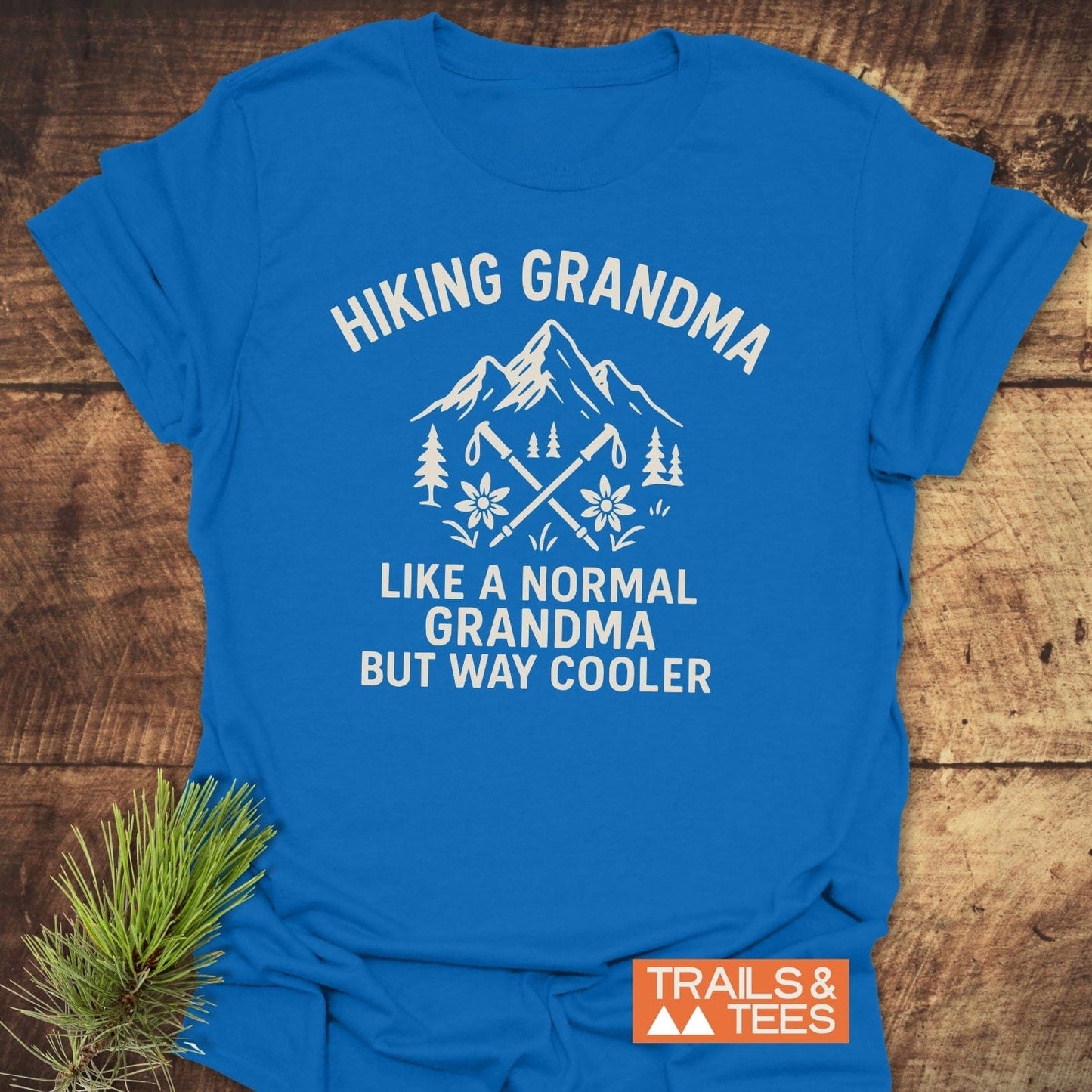 Hiking Grandma Mountain T-Shirt with stylized mountains, trees, and hiking poles. Features soft ring-spun cotton, durable prints, and eco-friendly production.